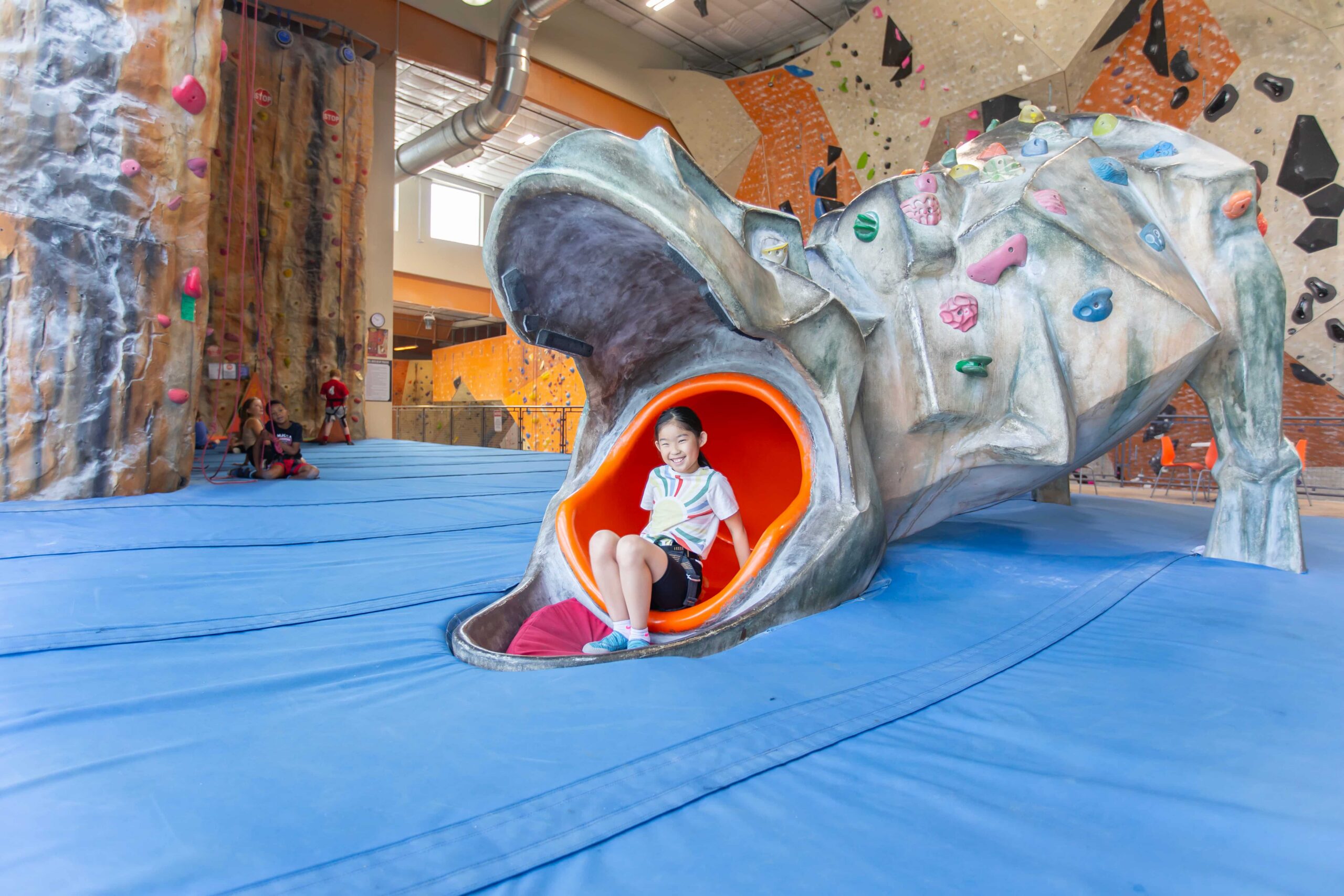 A girl sits inside a slide.