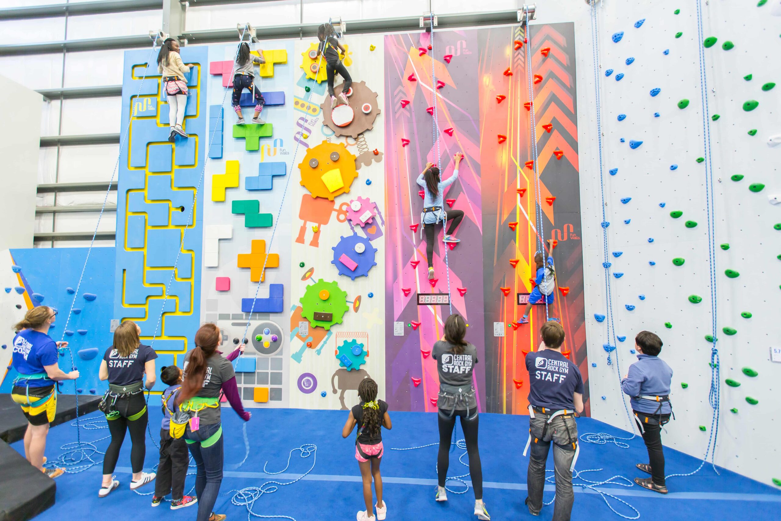 Kids climb on a party wall as CRG staff belay them