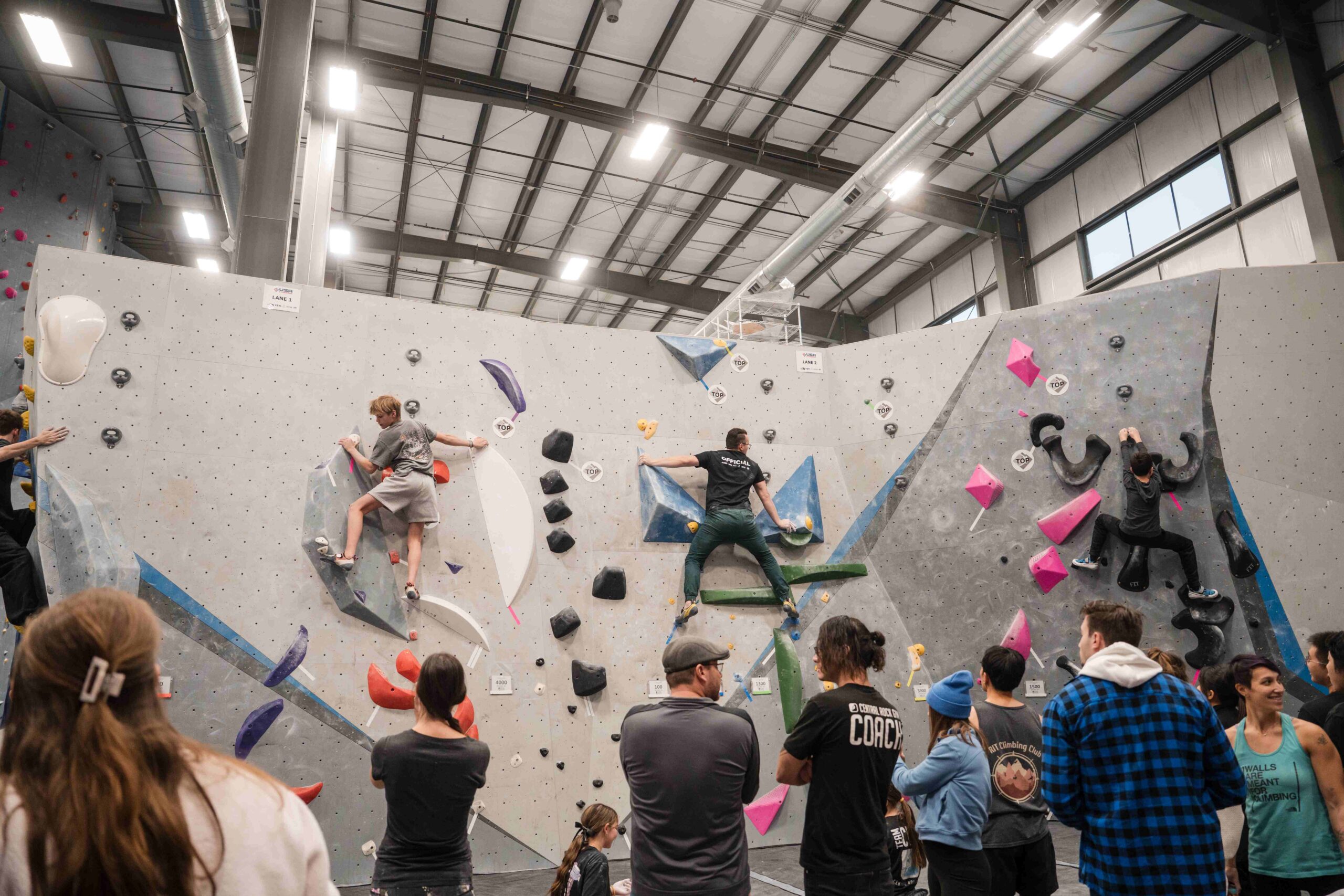 four boulderers attempt climbs in front of a crowd of spectators at crg buffalo