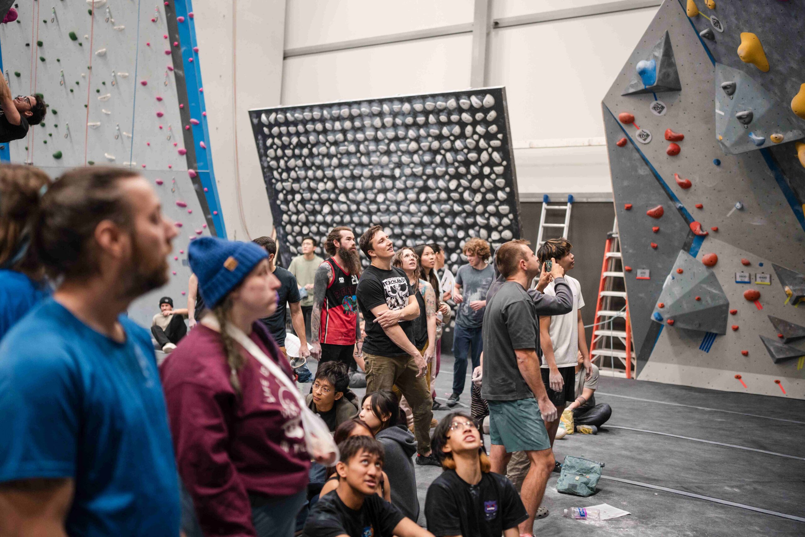 a crowd of climbers at crg buffalo watch another climber attempt a boulder problem