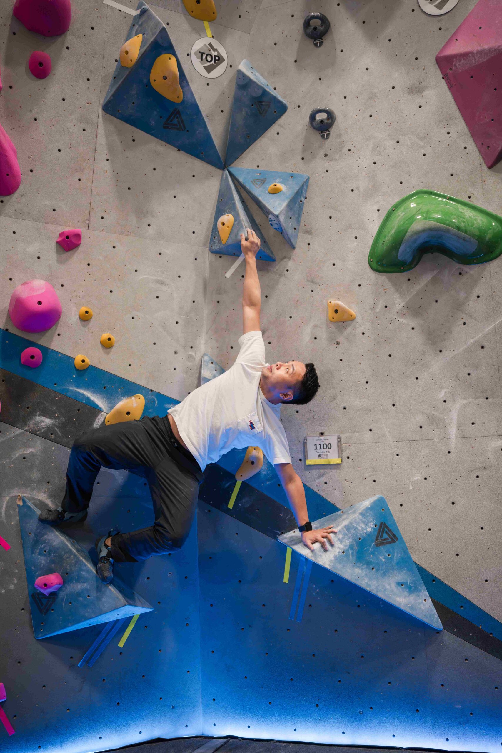 a climber is horizontal and stretched fully to attempt a unique bouldering move
