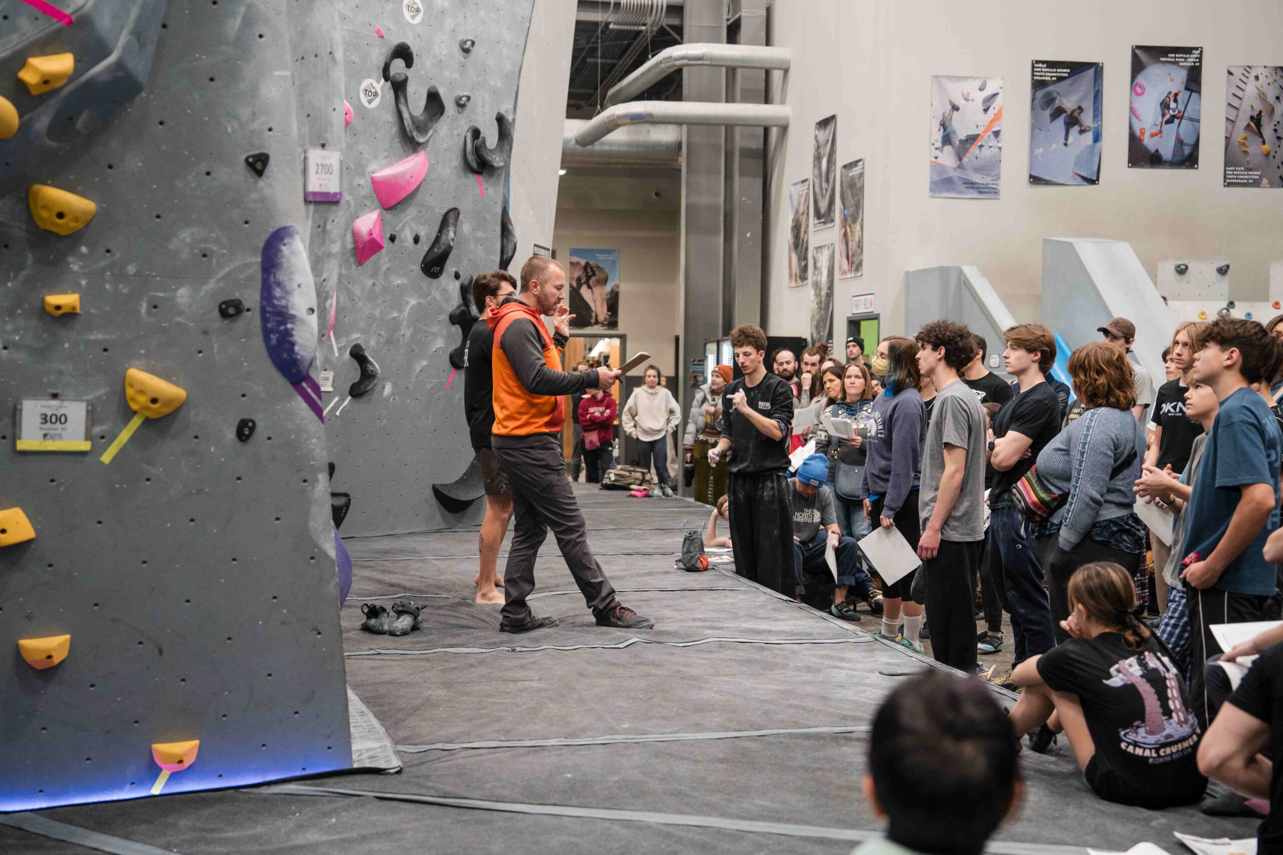 an emcee reads rules for climbing competition to a large group of competitors