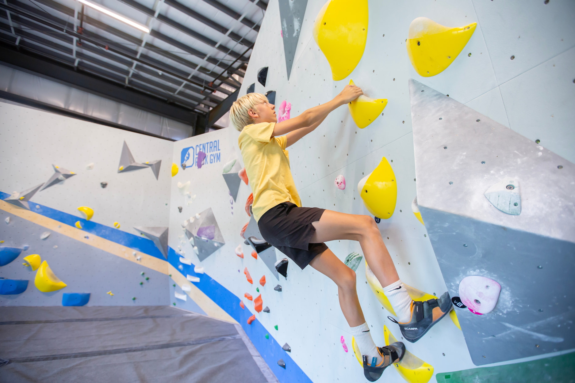 A pre-teen boy boulders at Central Rock Gym.