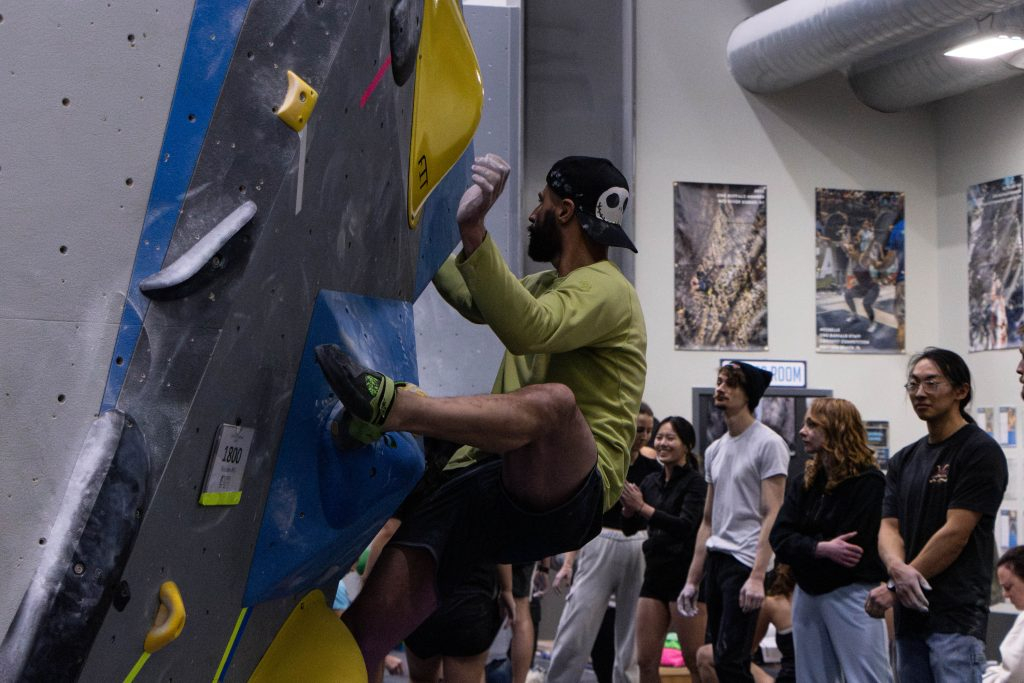image of a man bouldering with other climbers watching at central rock gym buffalo