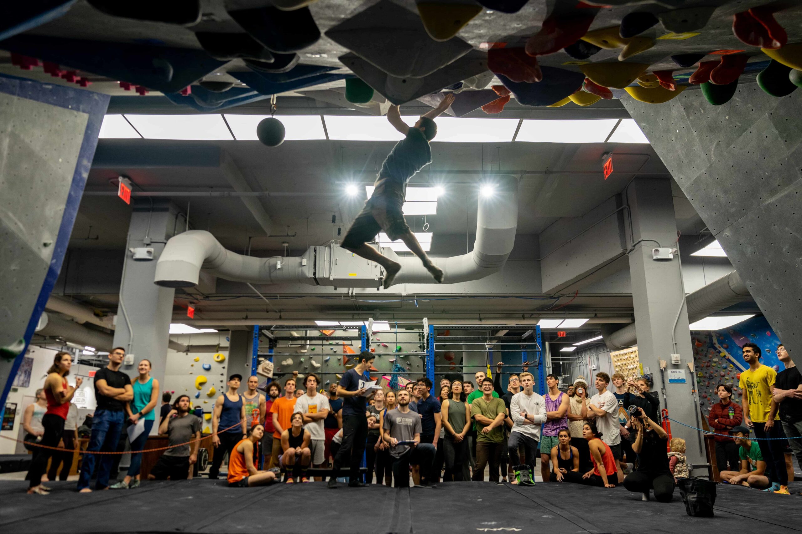 The silhouette of a man campusing as a crowd of people watch on.
