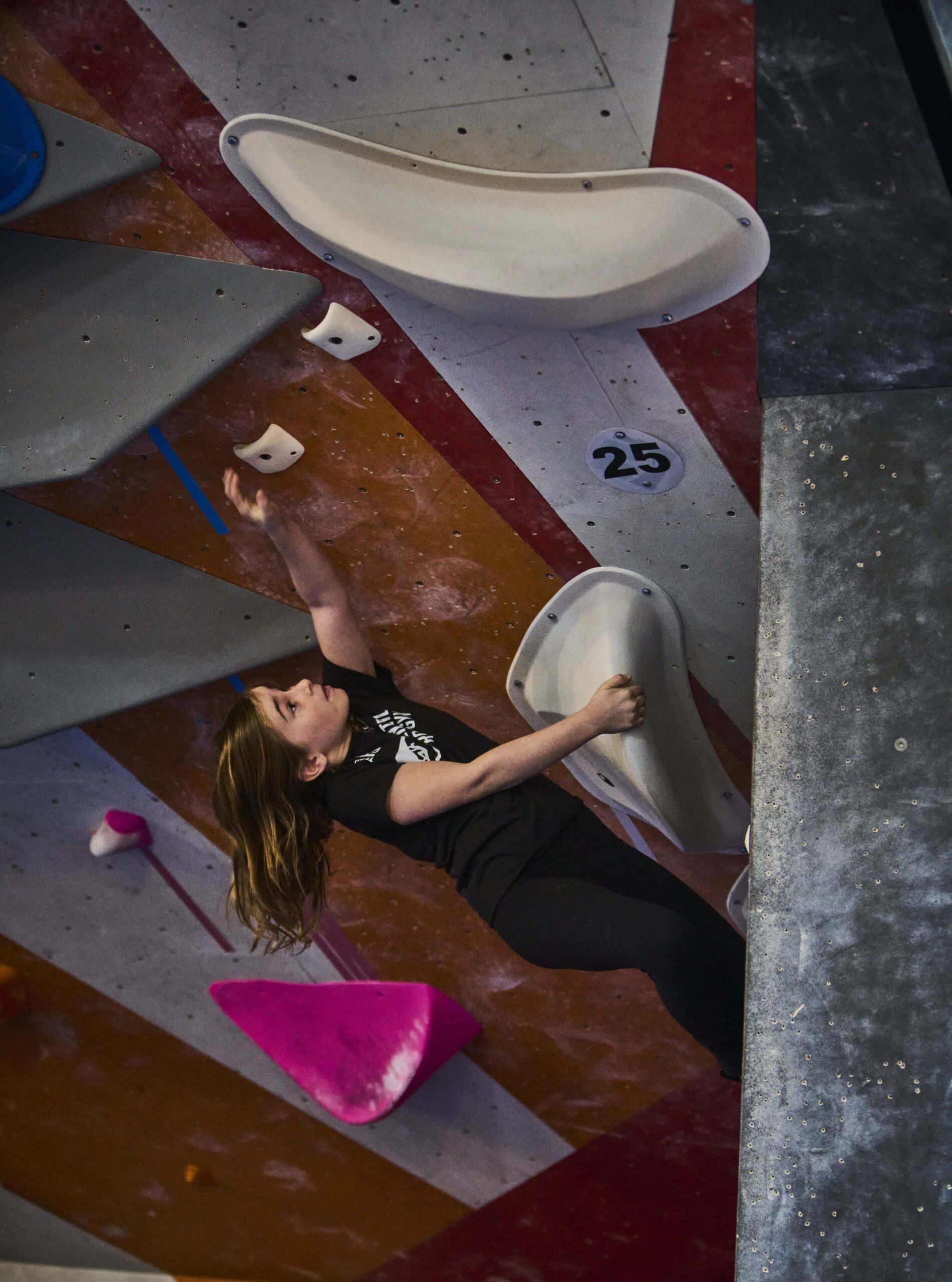 an athlete reaching for a small hold on a steep wall