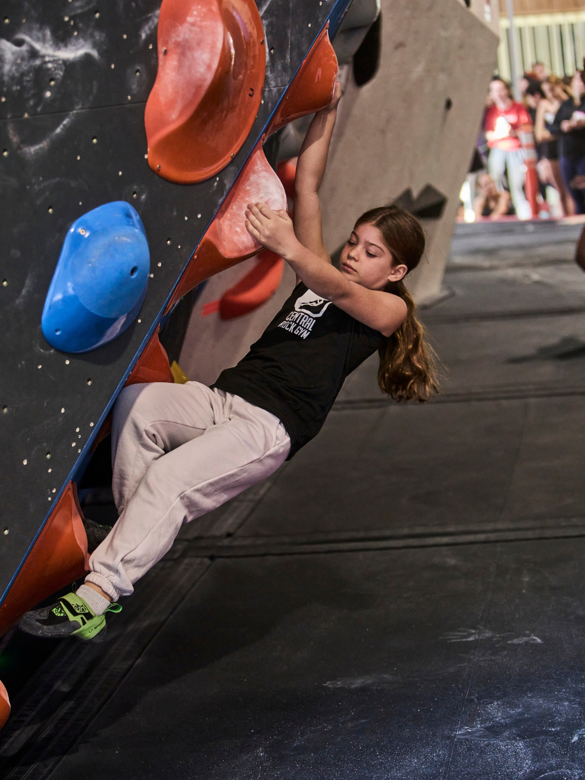 a young girl moves her foot on a steep climbing wall