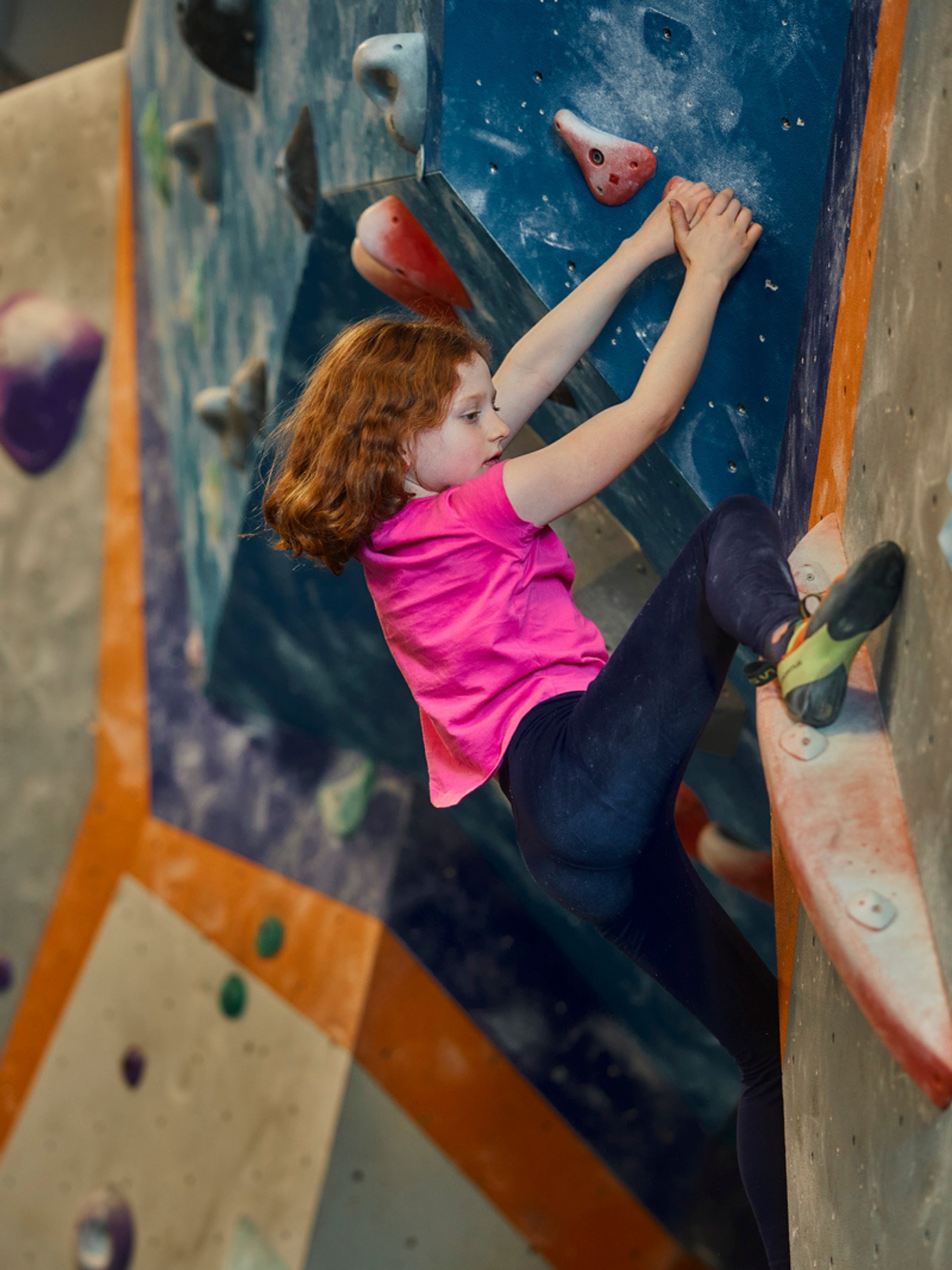 a young girl does a heel hook on the wall