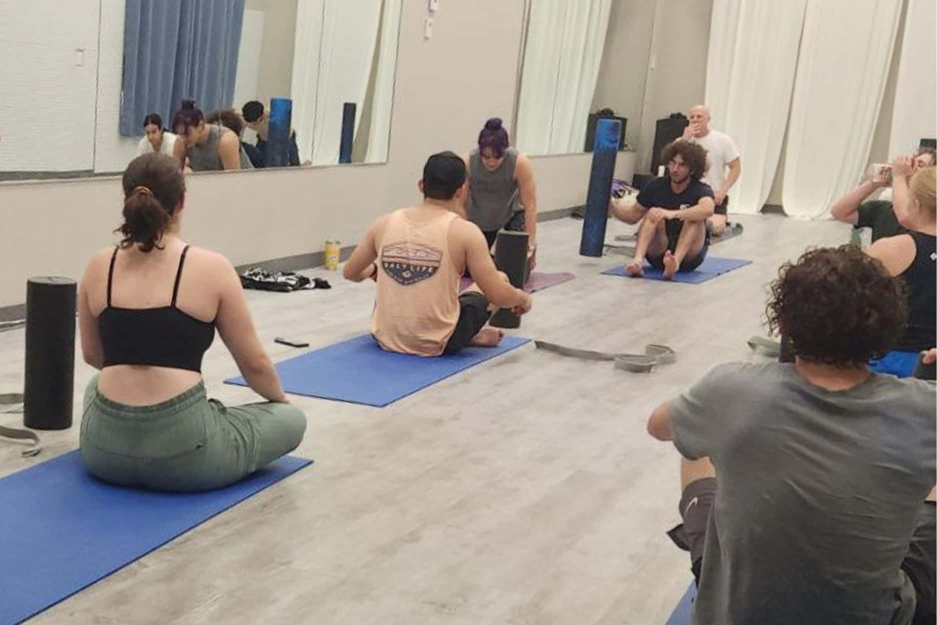 A class completes mobility together using foam rollers as an instructor guides them.