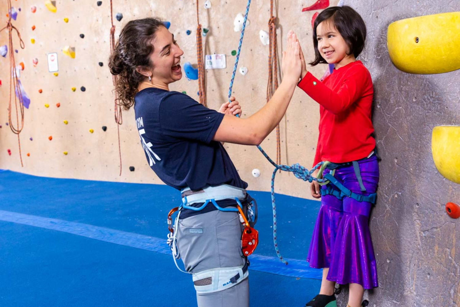 A kid high-fiving a staff member after climbing