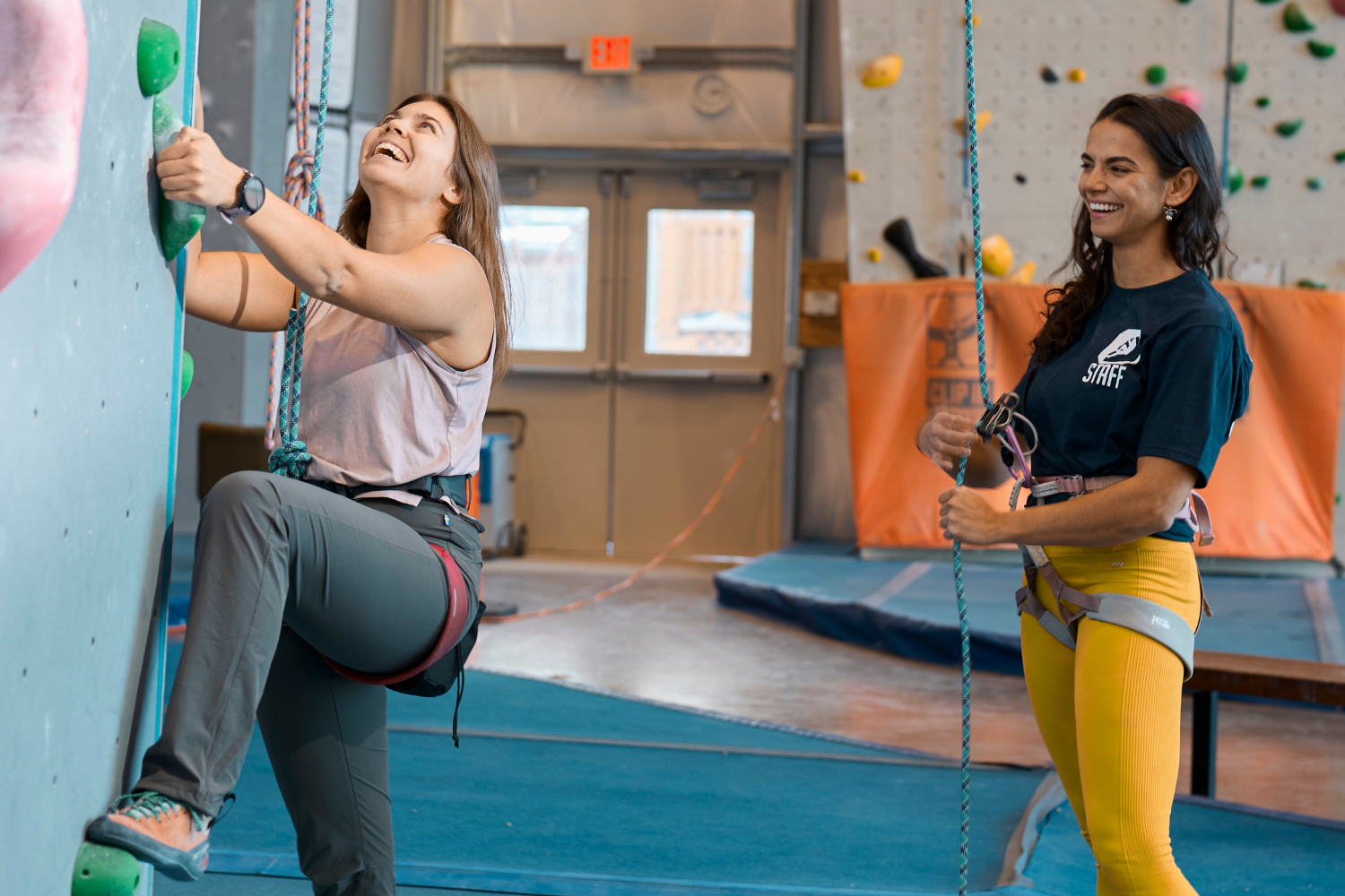 A person starting a climb with a staff member belaying them.