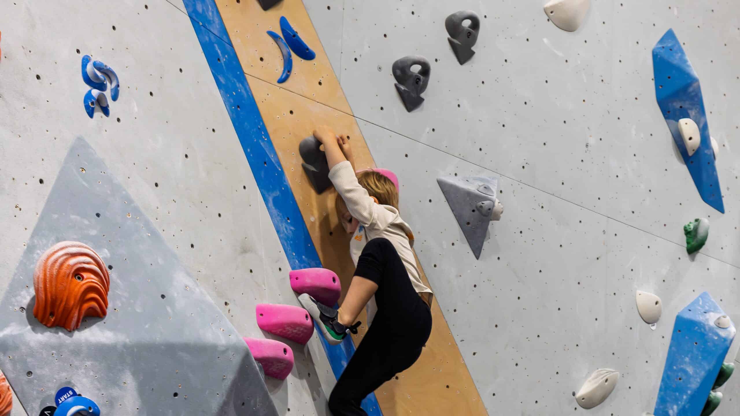 A young boy steps his foot up high as he boulders at Central Rock Gym during a kids program.