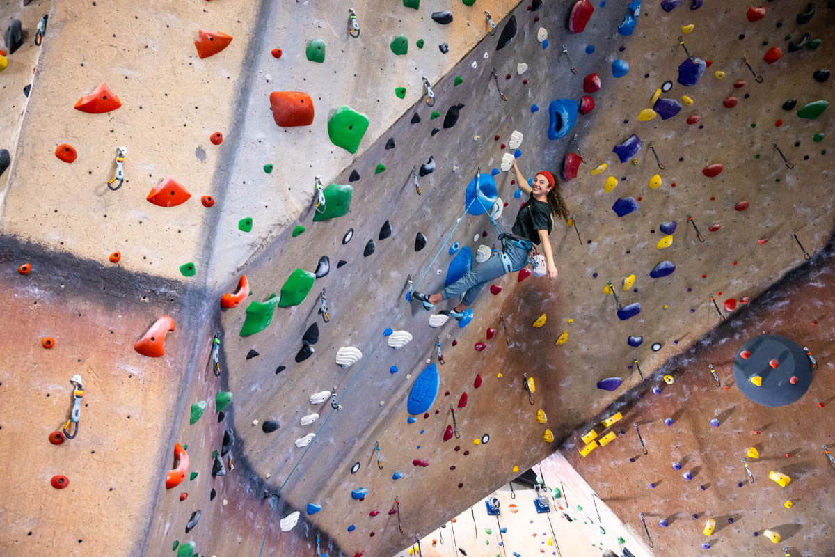 A teen girl lead climbs on an archway.
