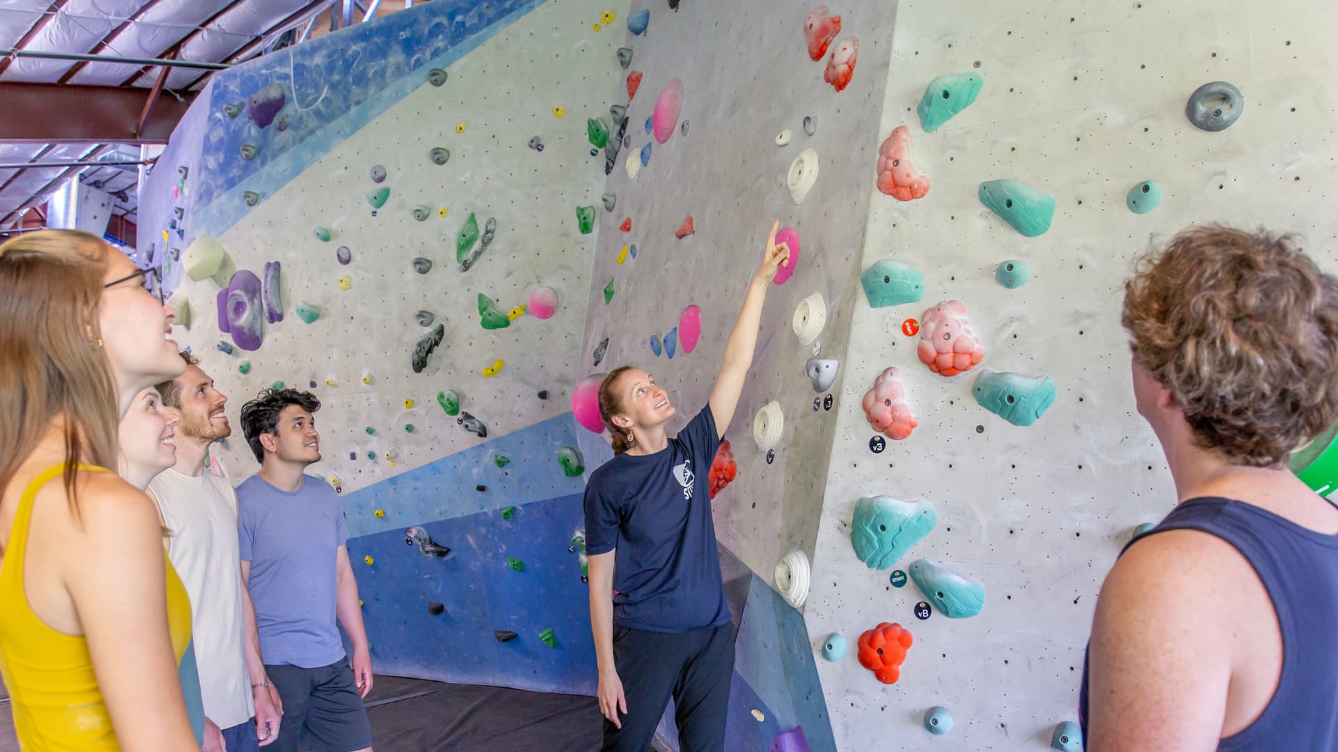 Central Rock Gym climbing instructor points out a type of move to a technique class.
