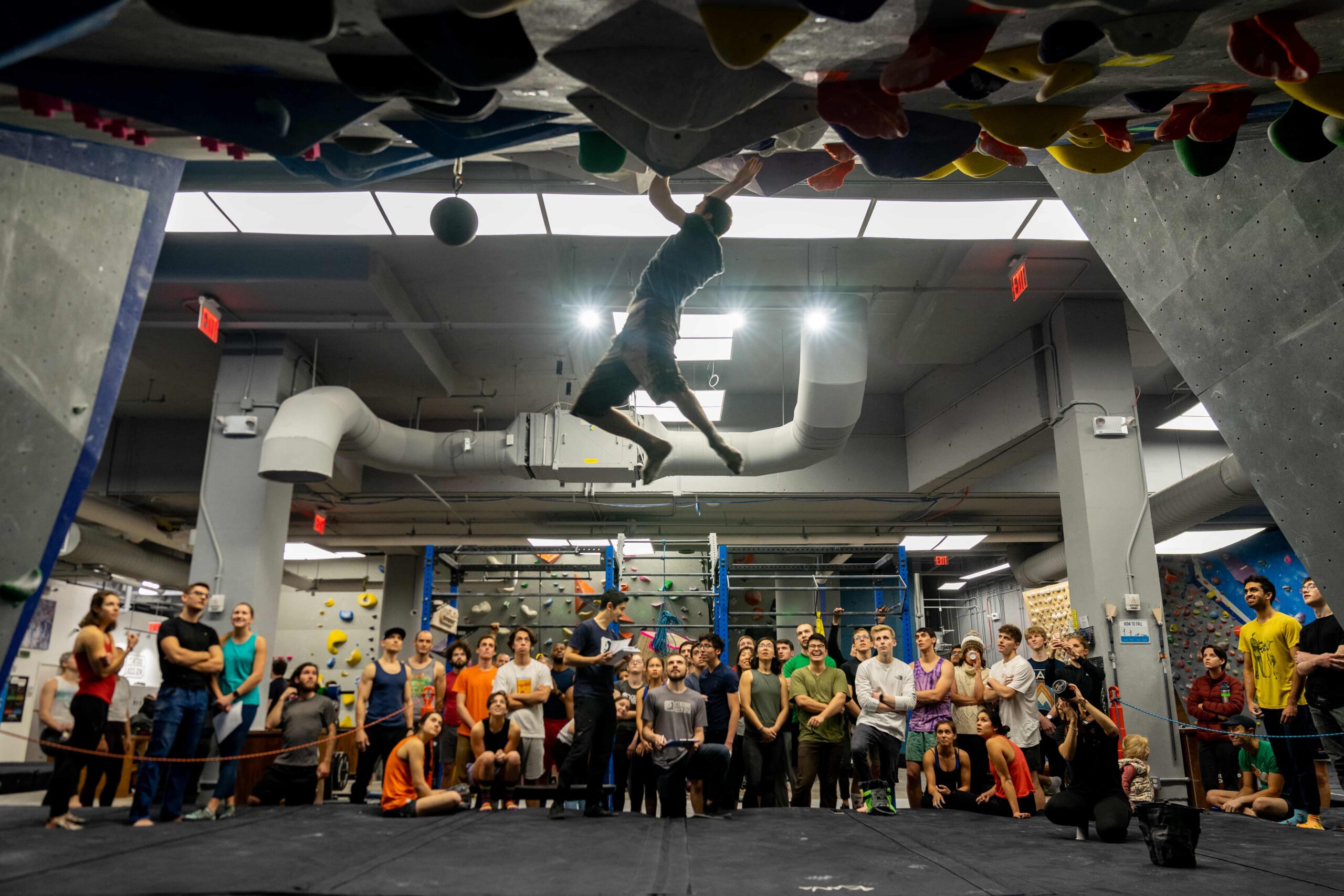 The silhouette of a man campusing as a crowd of people watch on.