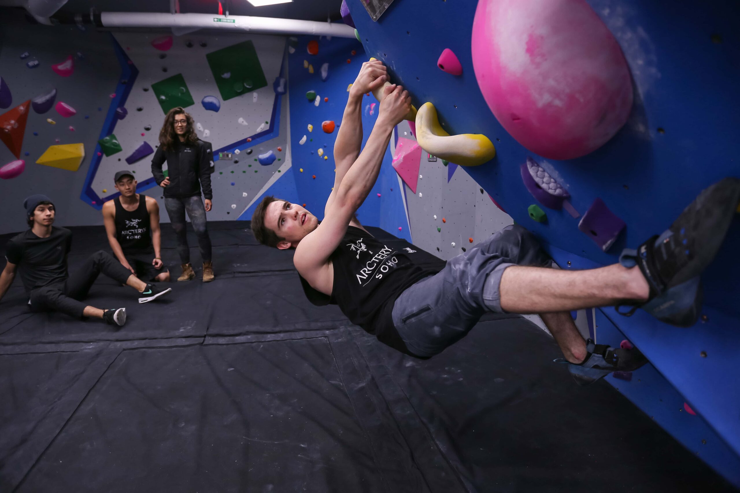A man is horizontal to the ground as he stretches his legs out and boulders.