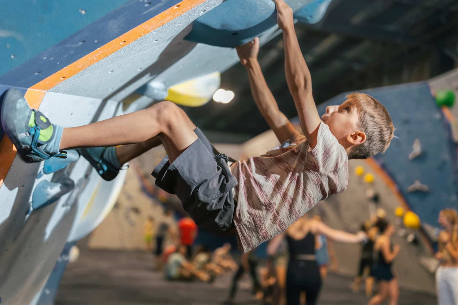 A boy boulders on a very steep overhang.