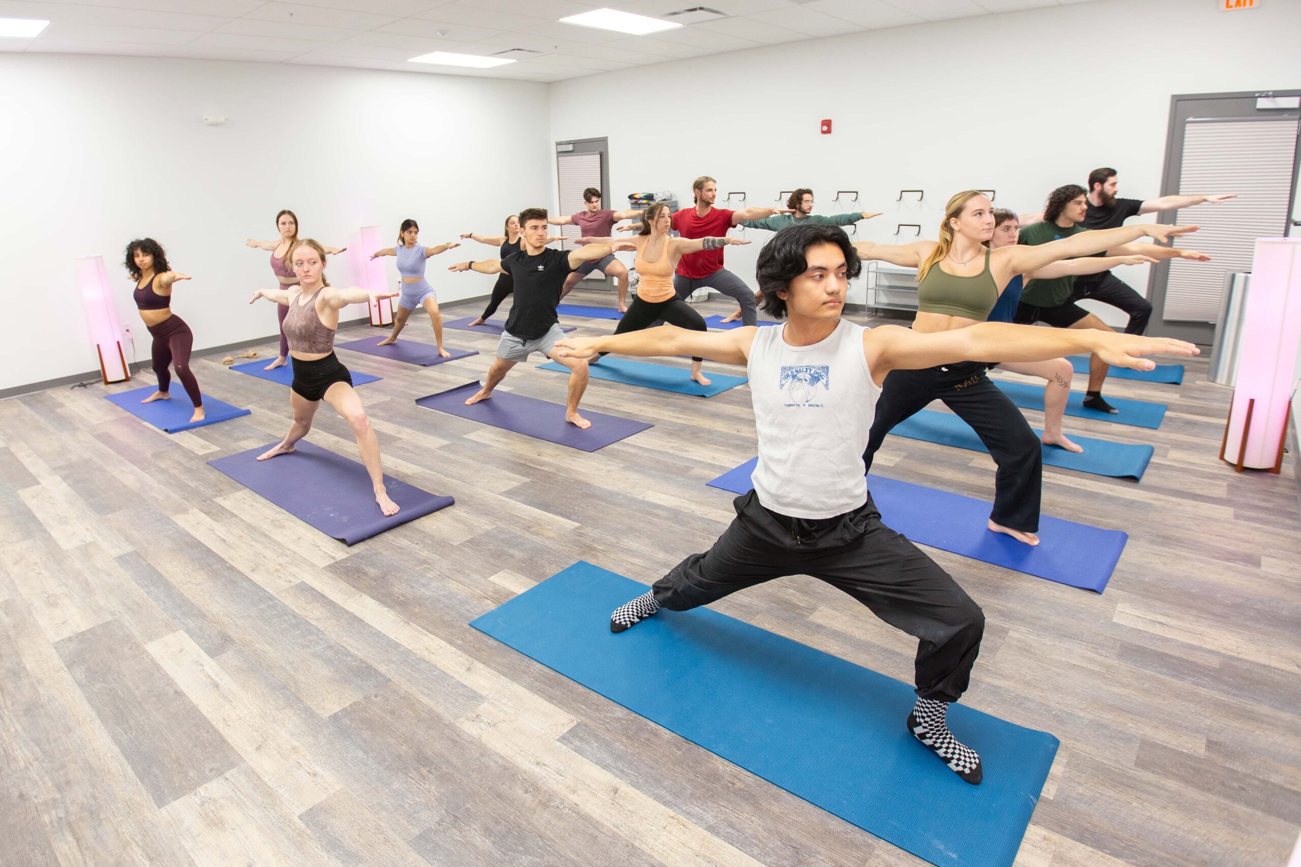 A group of people pose in Warrior 2 in a yoga class
