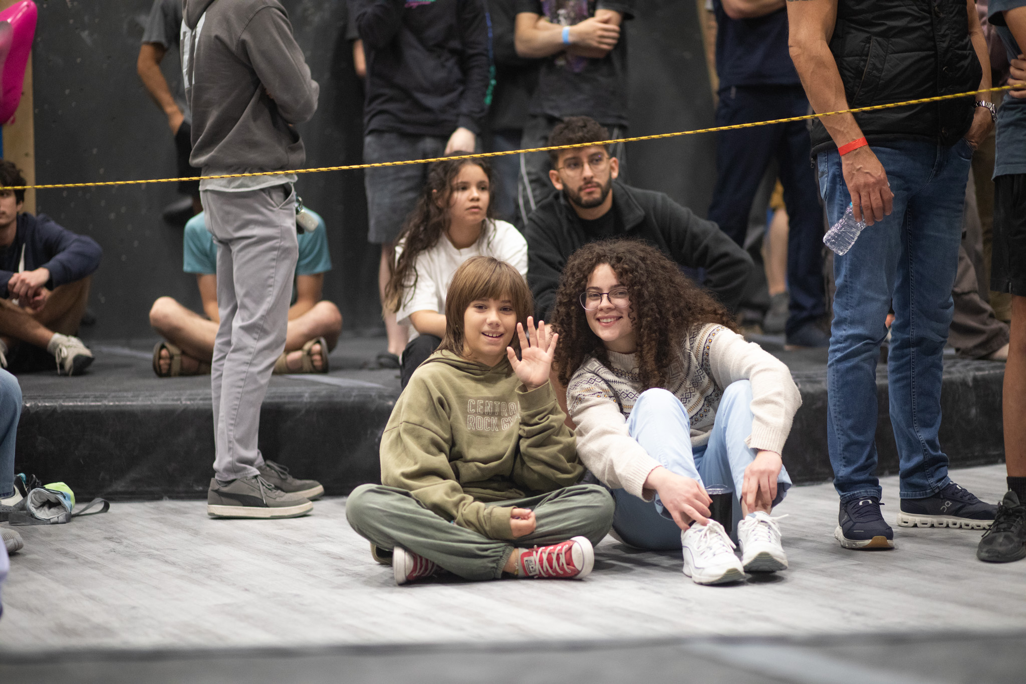 two spectators smiling at the camera while others are watching the event.