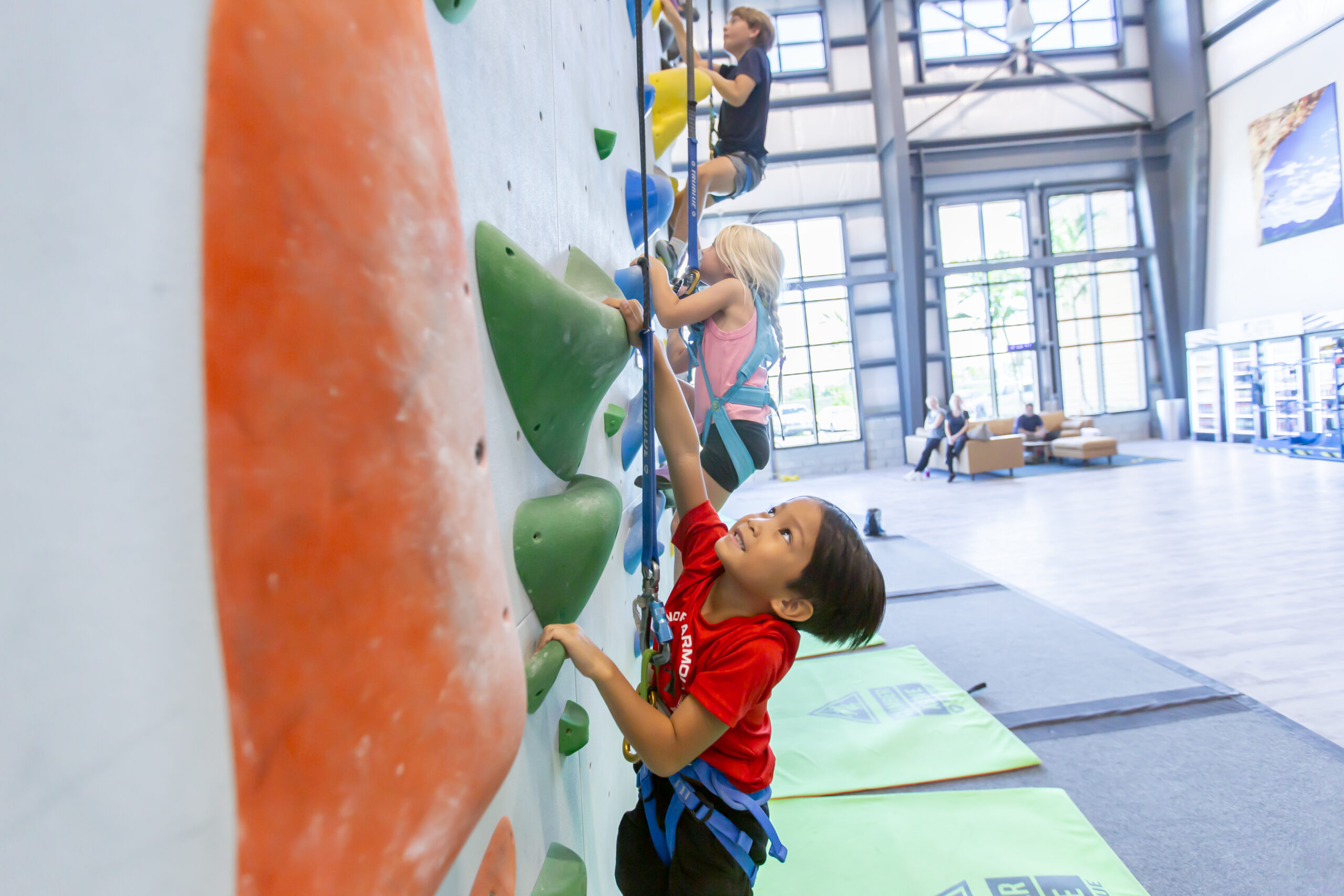 Young boy rock climbing and looking up at Central Rock Gym Randolph