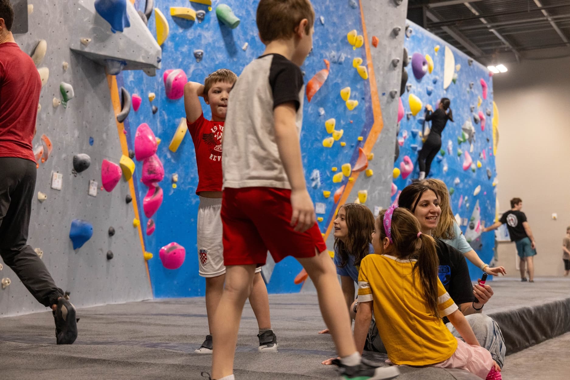 Young climbers in the bouldering area with coach having fun
