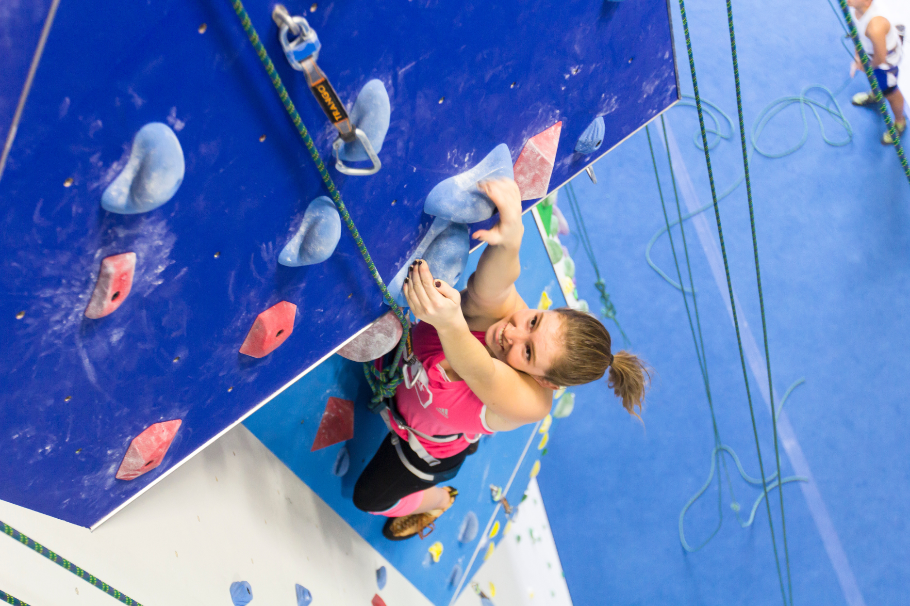 A young girl climbs a roped climb
