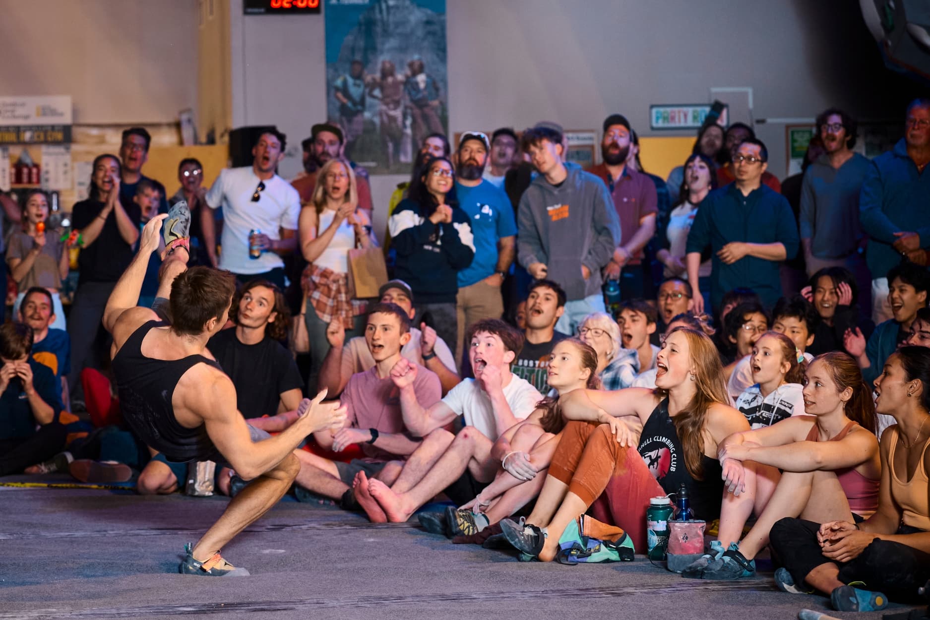 Male climber falls in the Canal Crusher bouldering finals, crowd in the background is visibly excited but expressing surprise and dismay