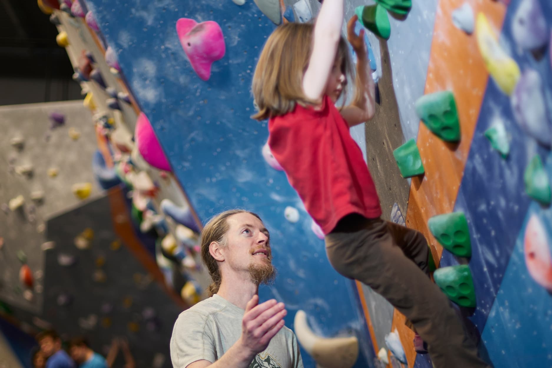 Young girl climbing in the bouldering area with her dad