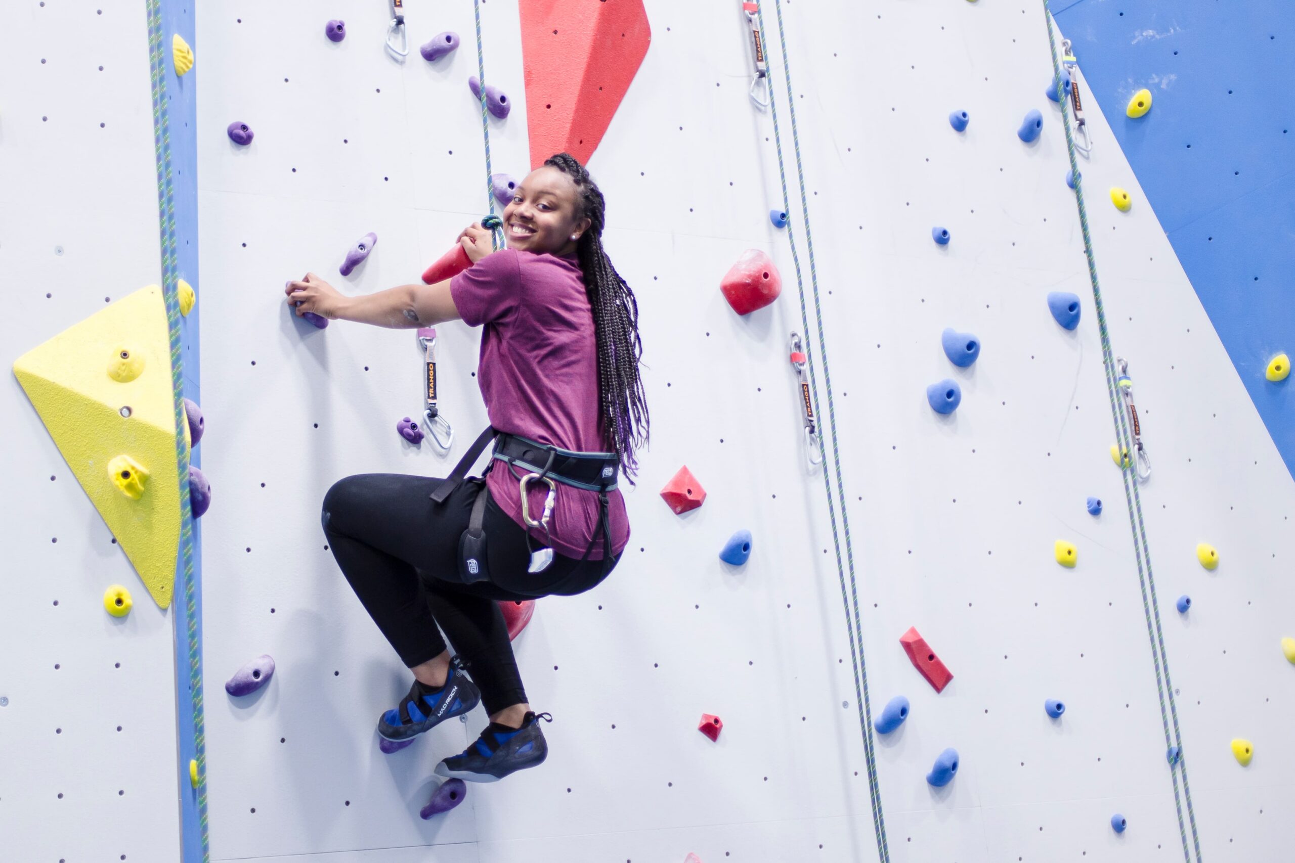 A girl with braids rests on the top rope wall.