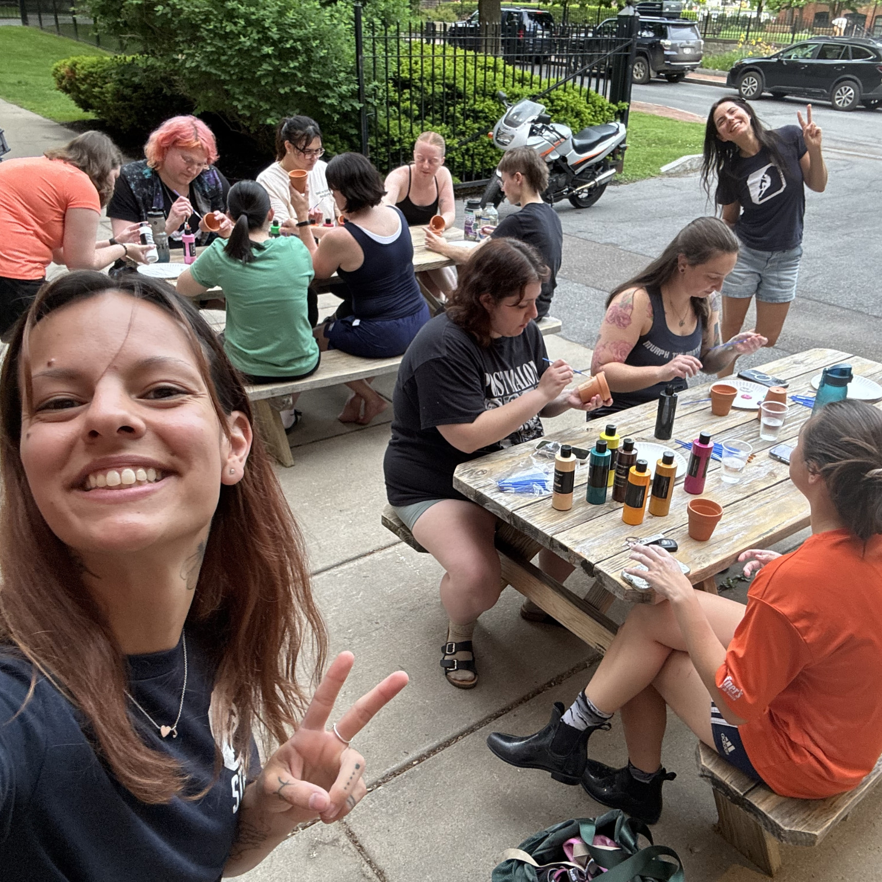 Women sitting outside CRG Syracuse painting mini flower pots following an evening of climbing.
