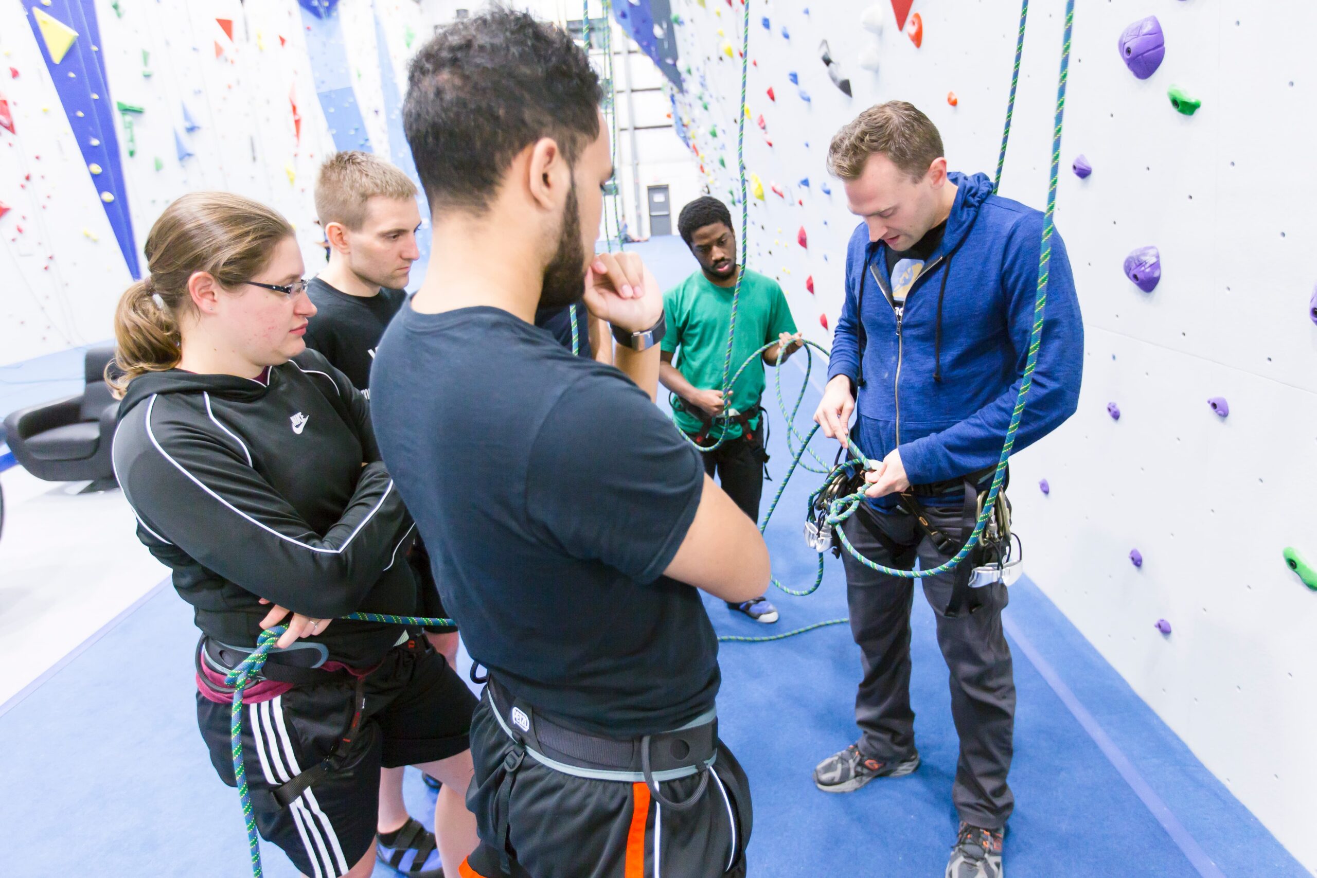Climbers learning to tie their knots from an instructor.