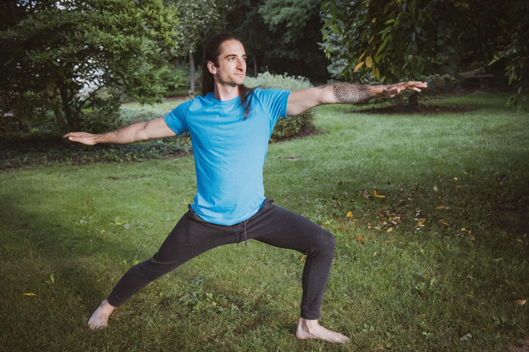 Yoga instructor outside posing in Warrior 2.