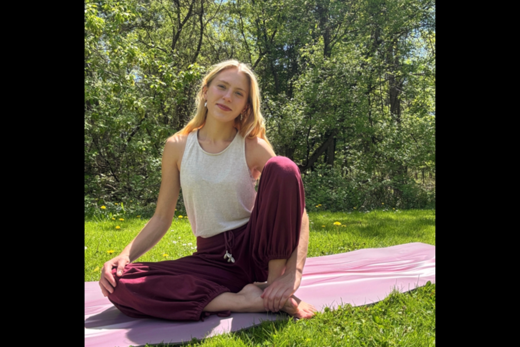 Yoga instructor sitting outside on her mat.