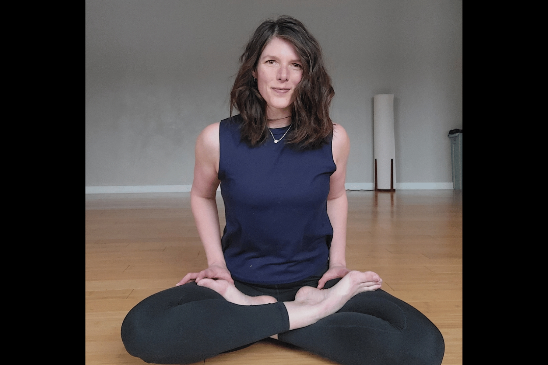 Yoga instructor sitting in lotus pose (legs crossed with feet above knees)