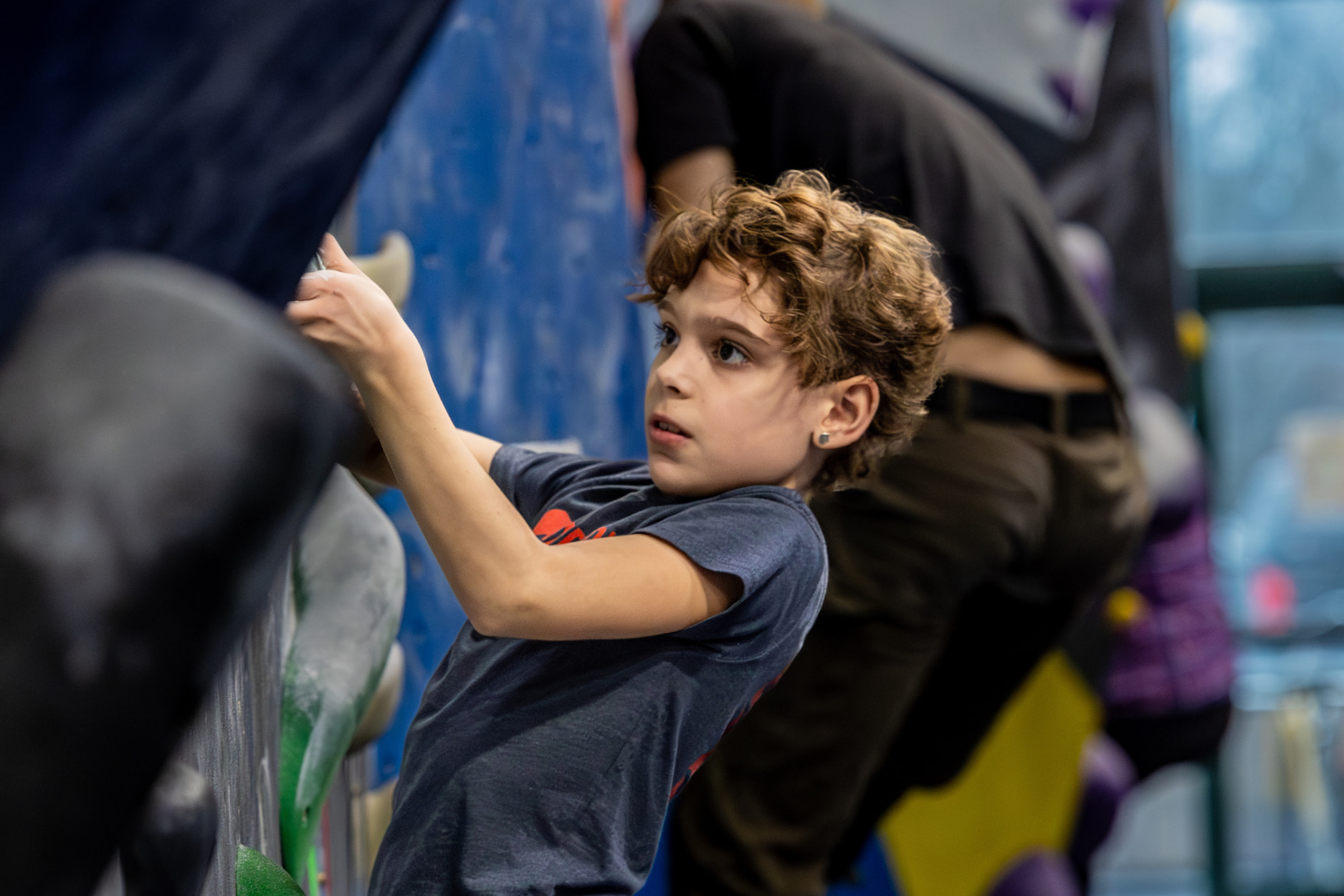 A young boy focuses as he boulders.