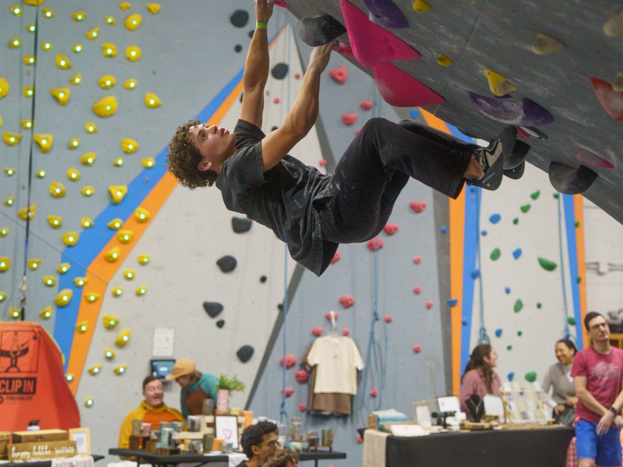Climber attempting a challenging overhanging boulder problem during a Boulders & Brews event.
