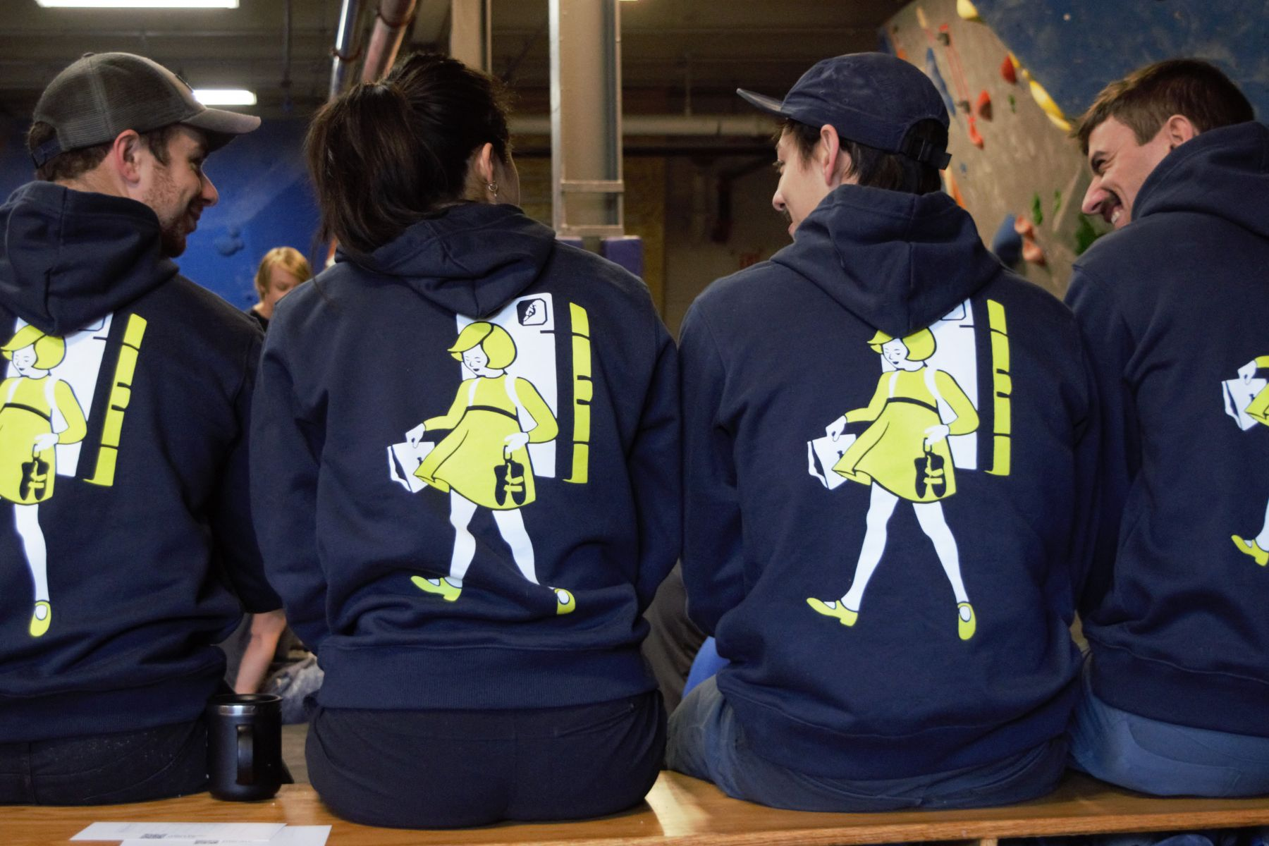 Members wearing event hoodies gather and socialize during a Boulders & Brews community event at Central Rock Gym Syracuse.