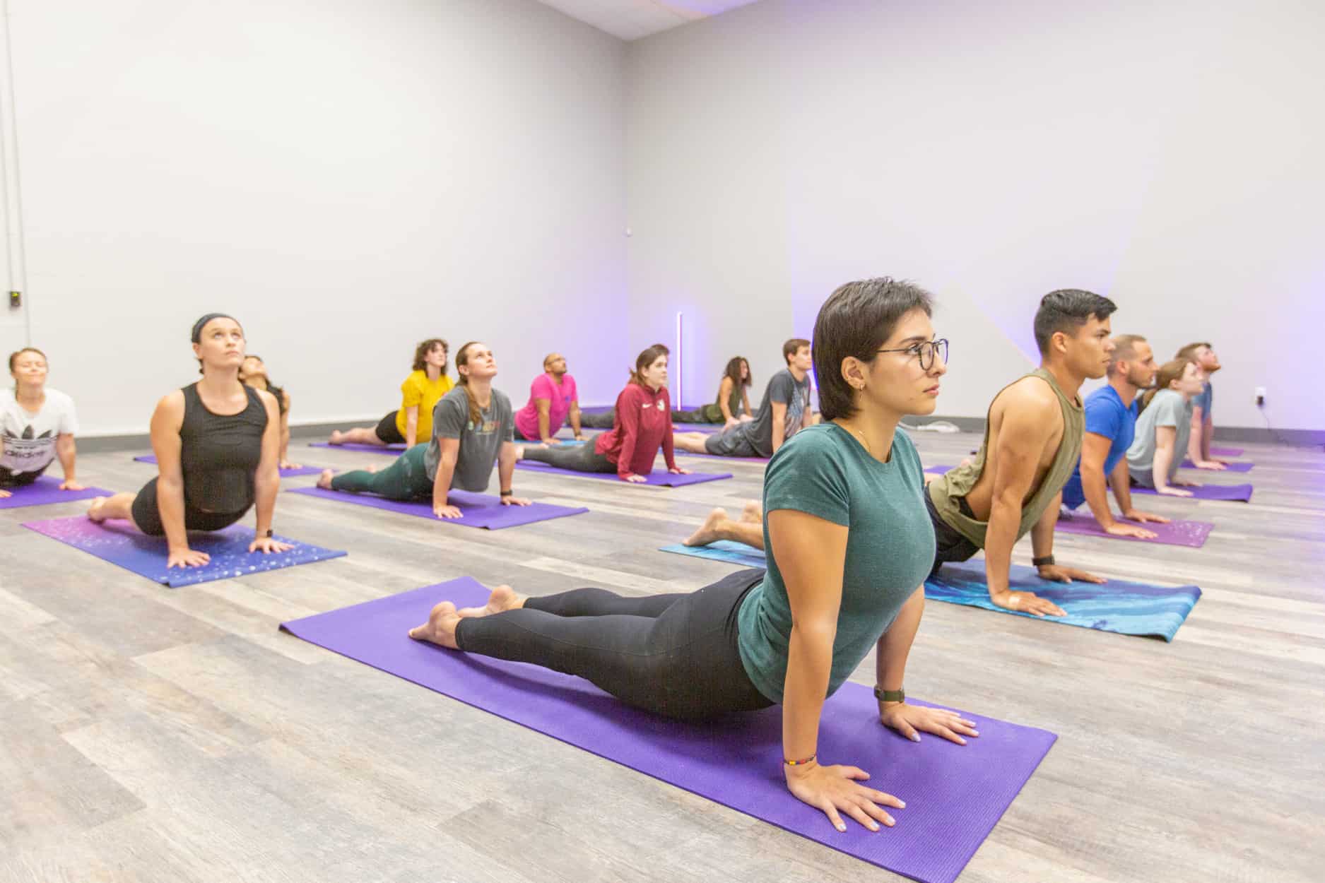 A yoga class poses in cobra pose together during a class at Central Rock Gym.
