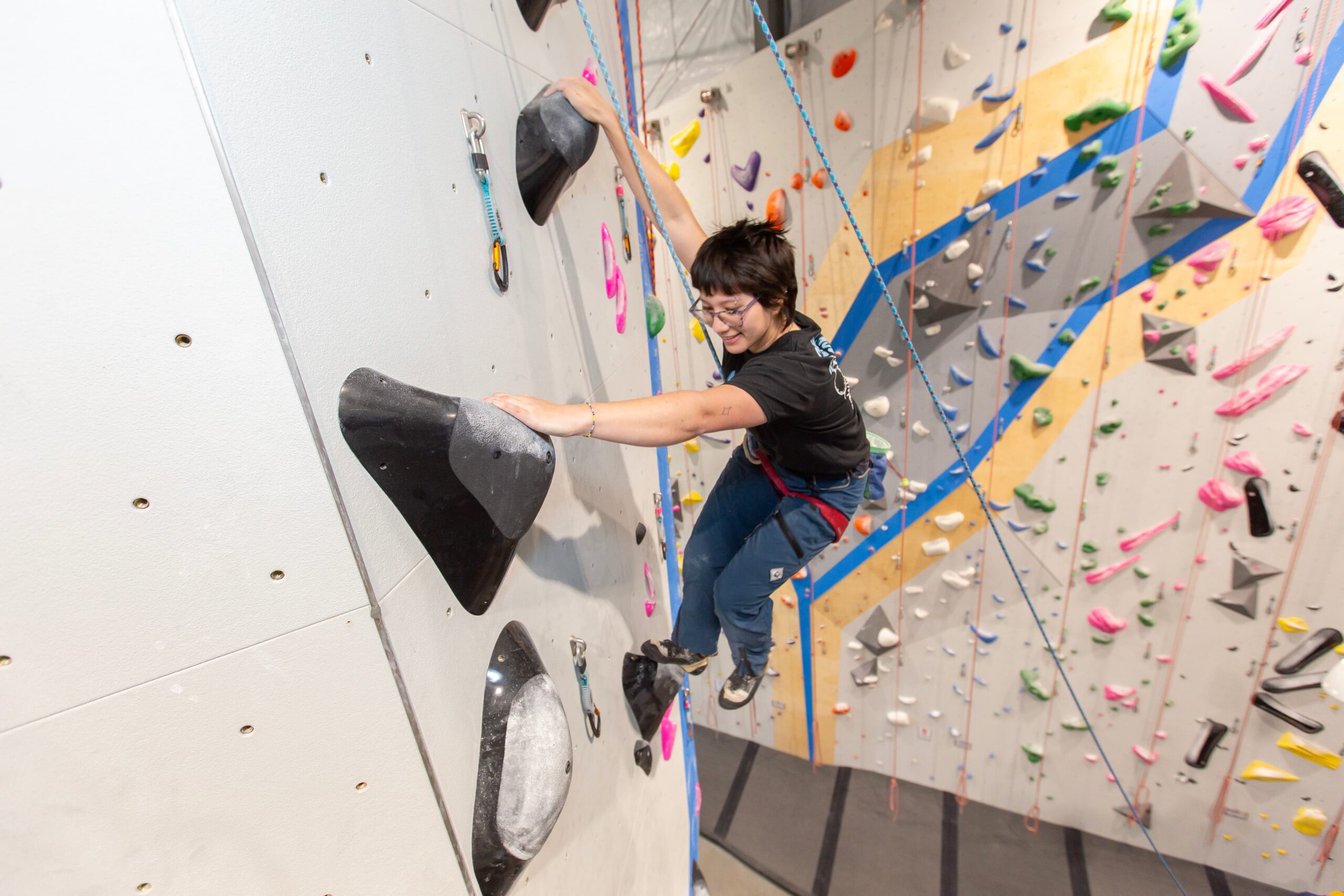 A girl is top rope climbing at Central rock gym