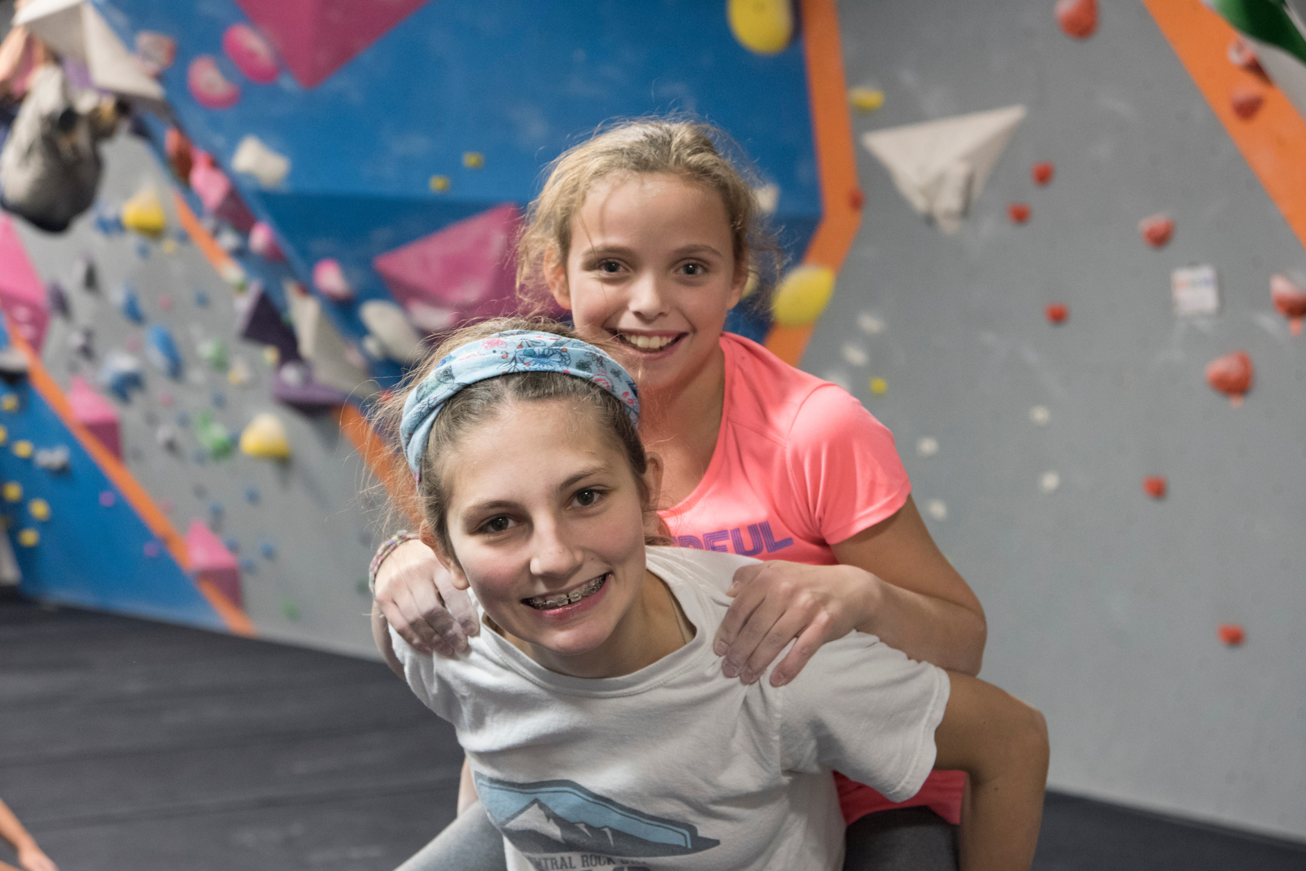 Two young girls giving eachother a piggy back ride.