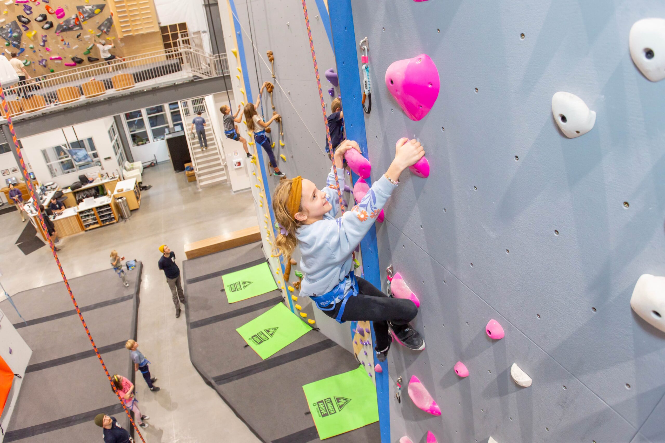 A young girl is top rope climbing at Central rock gym