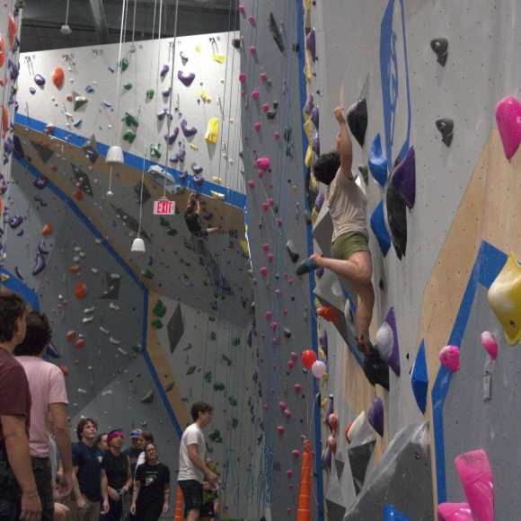 Folks watch a climber go for a dyno