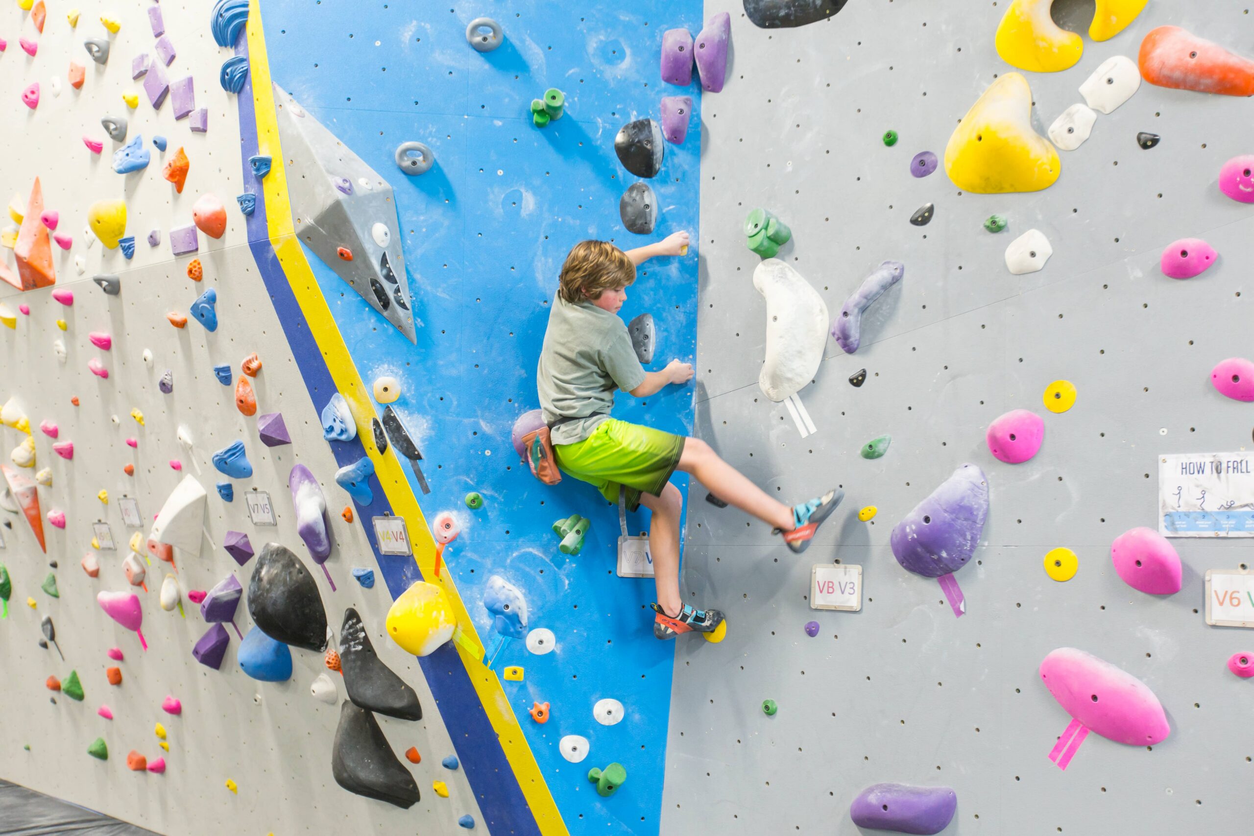 A young boy boulders in a dihedral.