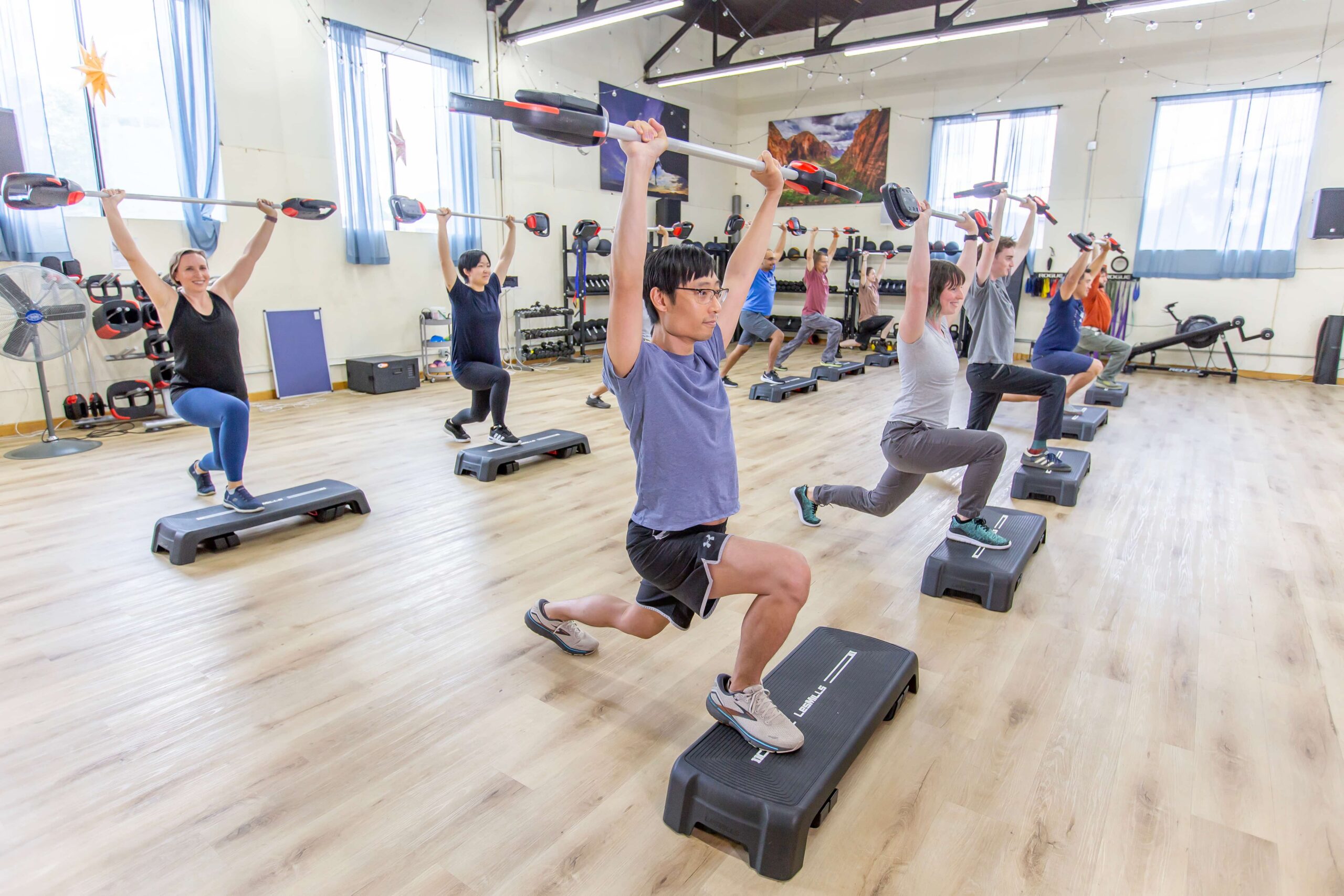 Customers lifting weights over their heads during body pump workout.