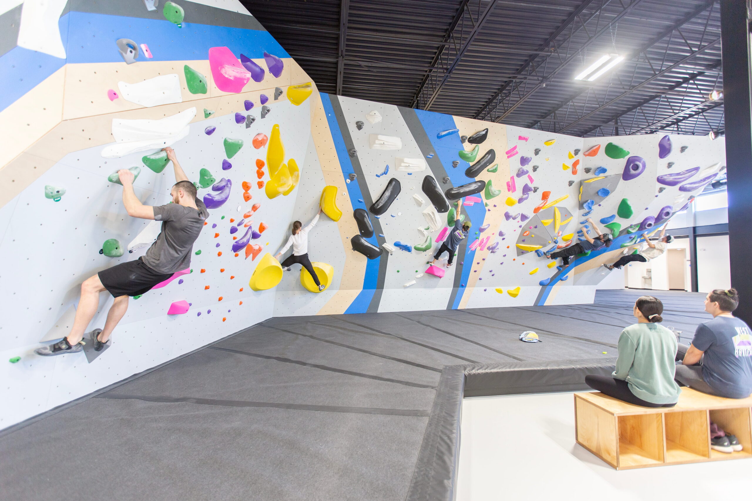 People are bouldering while others sit on the benches and watch on.