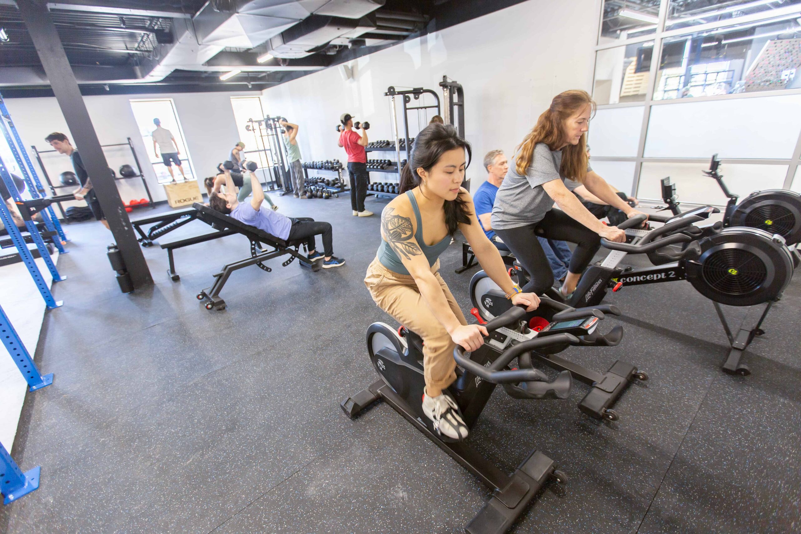 Two women workout on bikes.