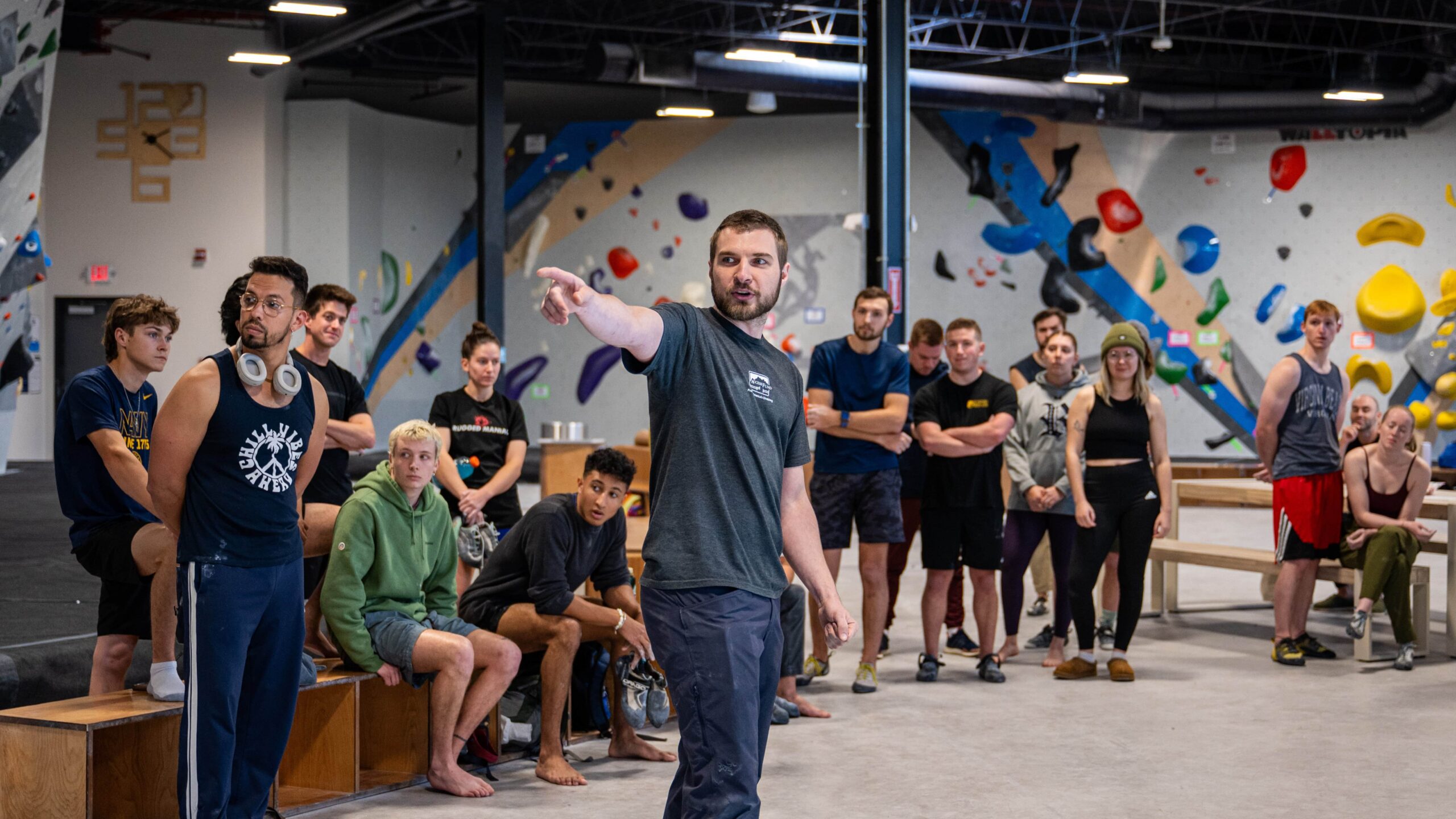 The rules meeting before a bouldering competition. CRG Staff points to the wall while explaining the rules.