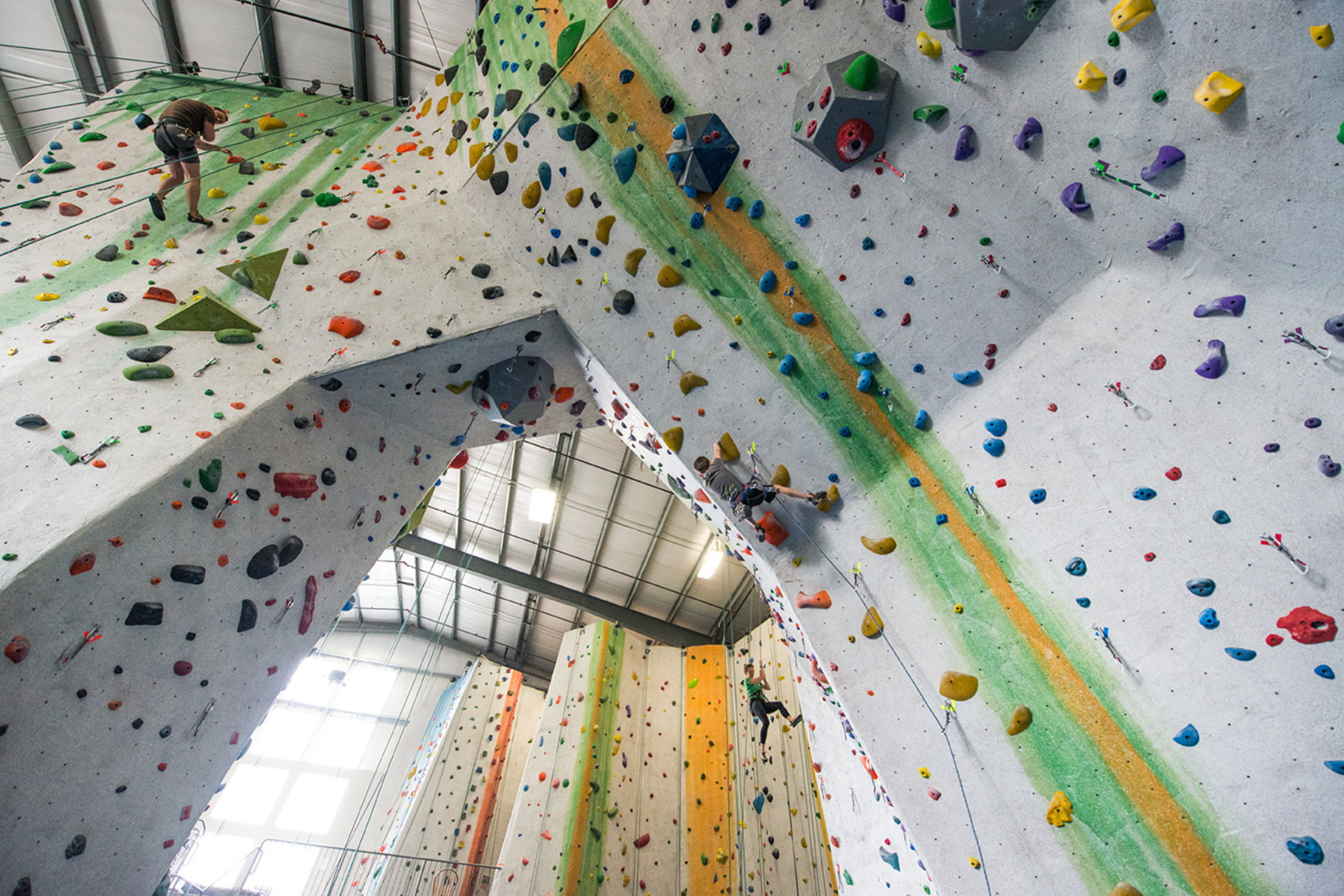 Two men rope climbing (lead and top rope) on an archway.