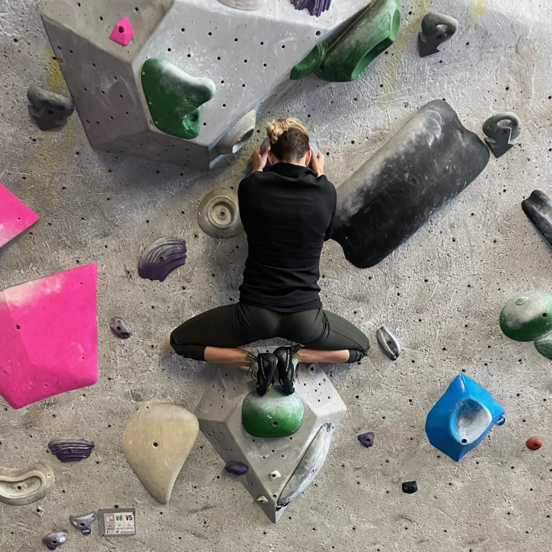 A woman in climbing a boulder showing great mobility in her hips by pivoting both knees outward.