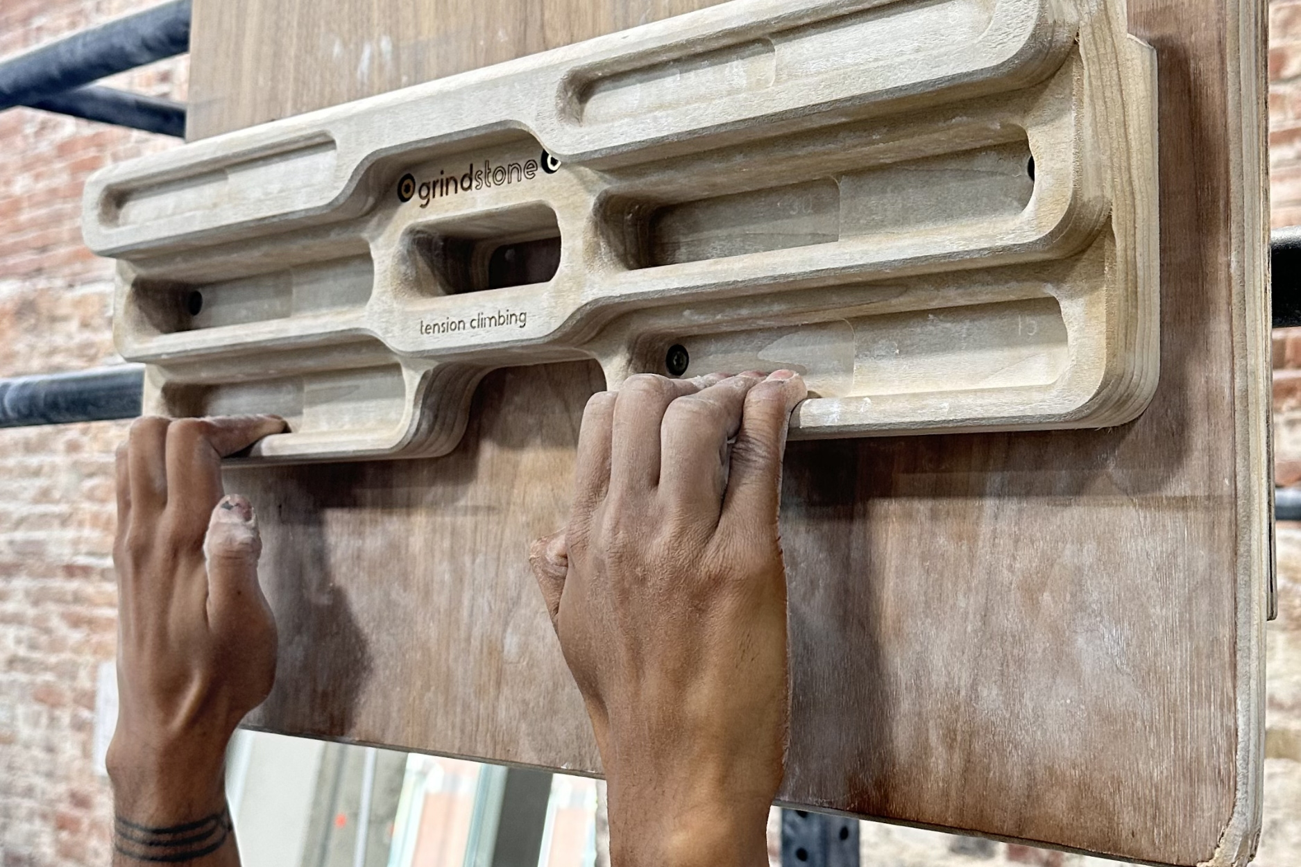 Someone's hands are shown with fingers engaged and hanging off of a hangboard at central rock gym.